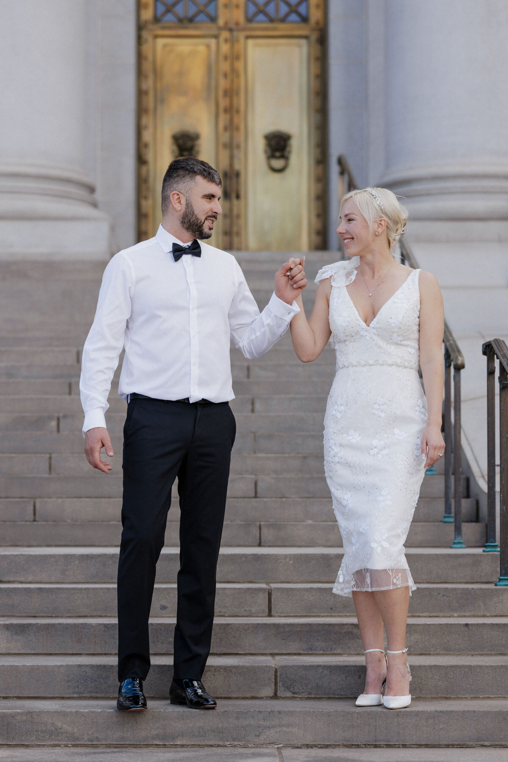 bride and groom walk down steps of denver courthouse during elopement day in colorado.