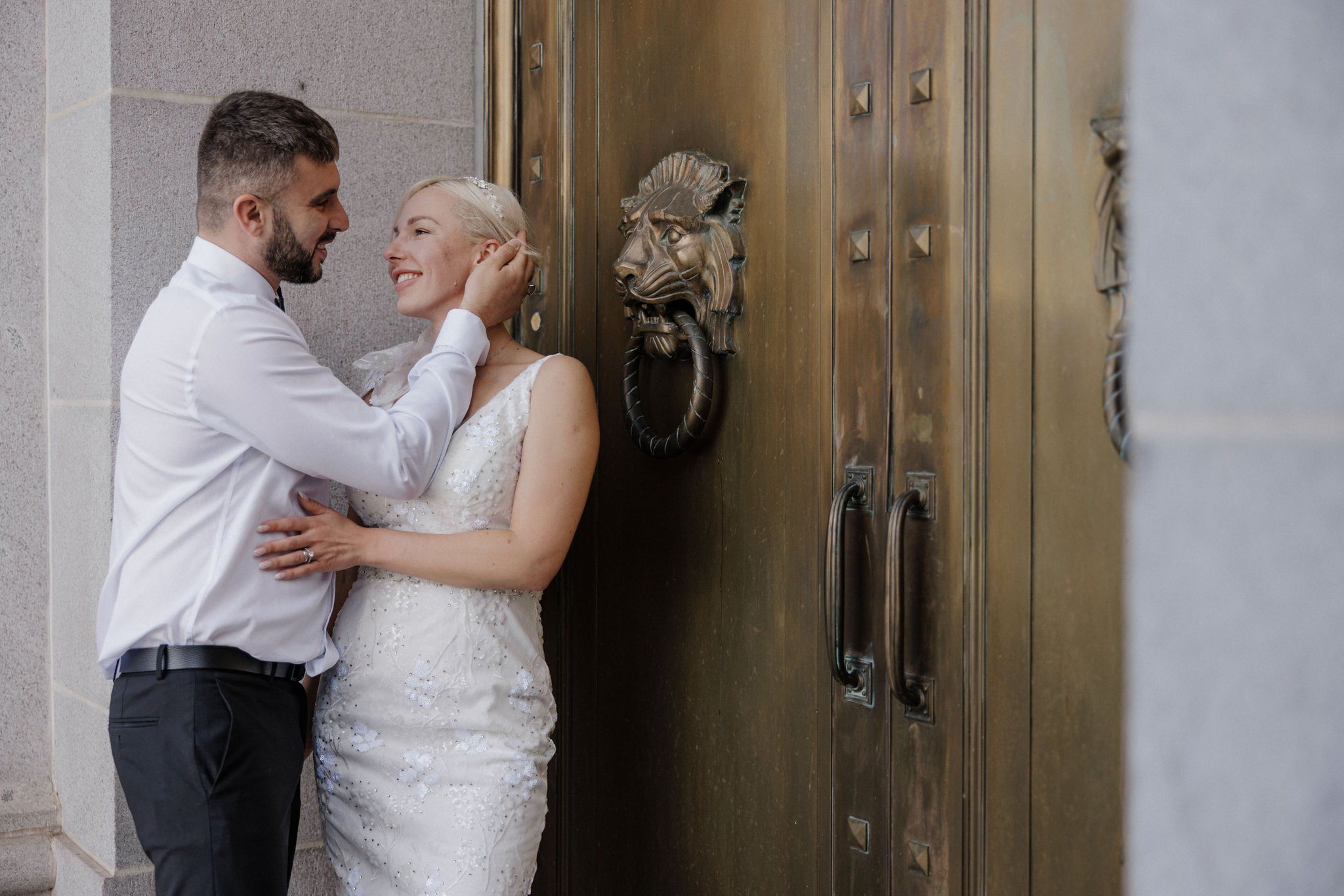 bride and groom lean against doors of denver courthouse doors during elopement.