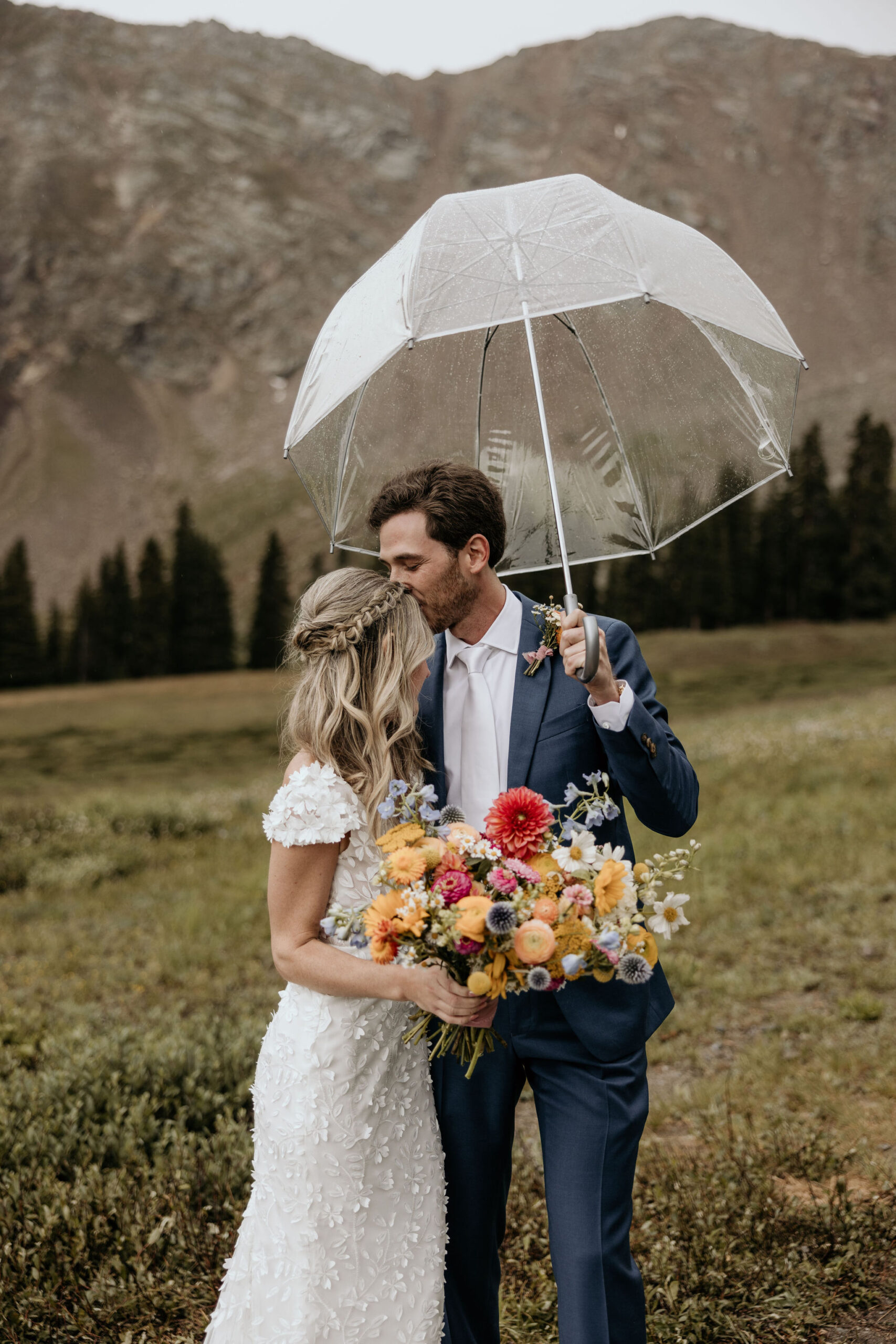 Why Renew Your Wedding Vows? Ideas, Reasons, + How-To: groom kisses bride and holds clear umbrella over them