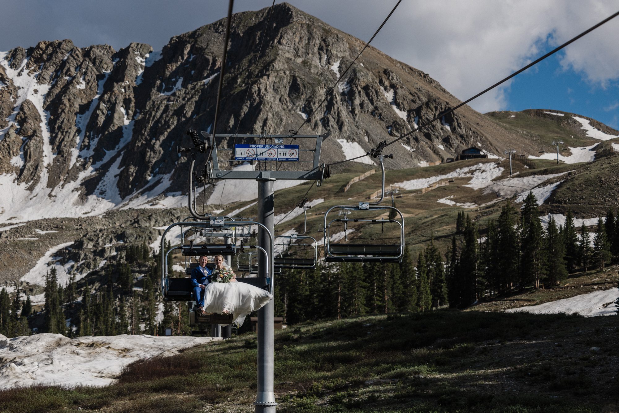 during their vow renewal in colorado, bride and groom ride the ski lift