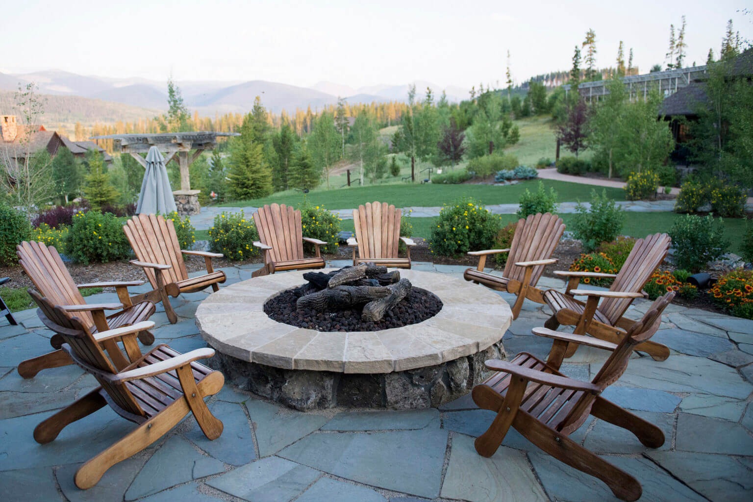 wooden chairs sit around a fire pit in the colorado mountains