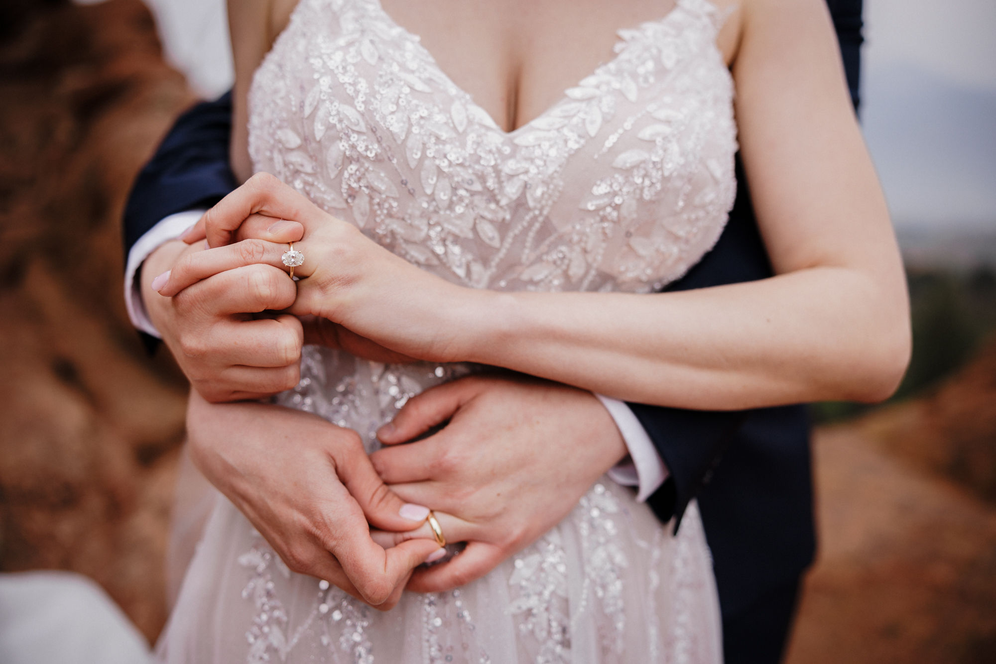 bride and groom hold each others rings during garden of the gods elopement