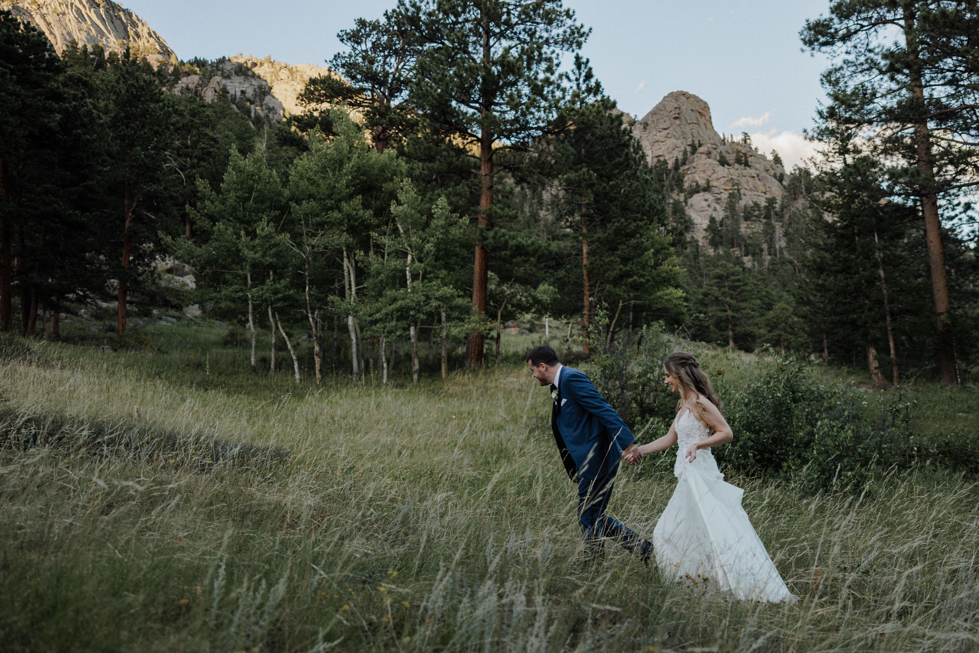 bride and groom walk up mountain at colorado micro wedding with a set budget.