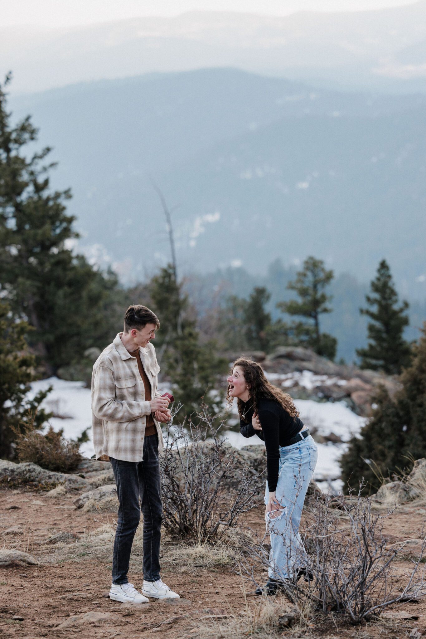 woman puts hand on her chest after being proposed to in colorado 