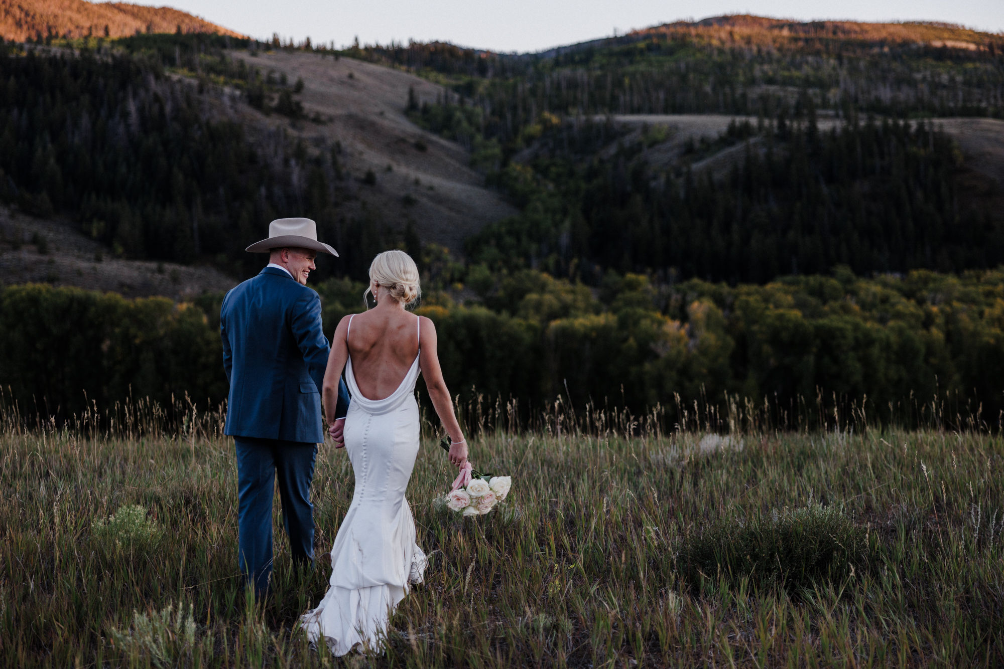 after completing their elopement planning checklist, bride and groom hold hands and walk through the colorado mountains