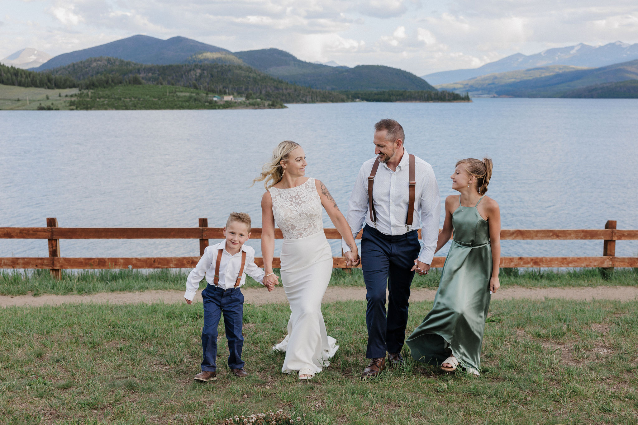 bride, groom, and children hold hands during wedding photos by a colorado lake