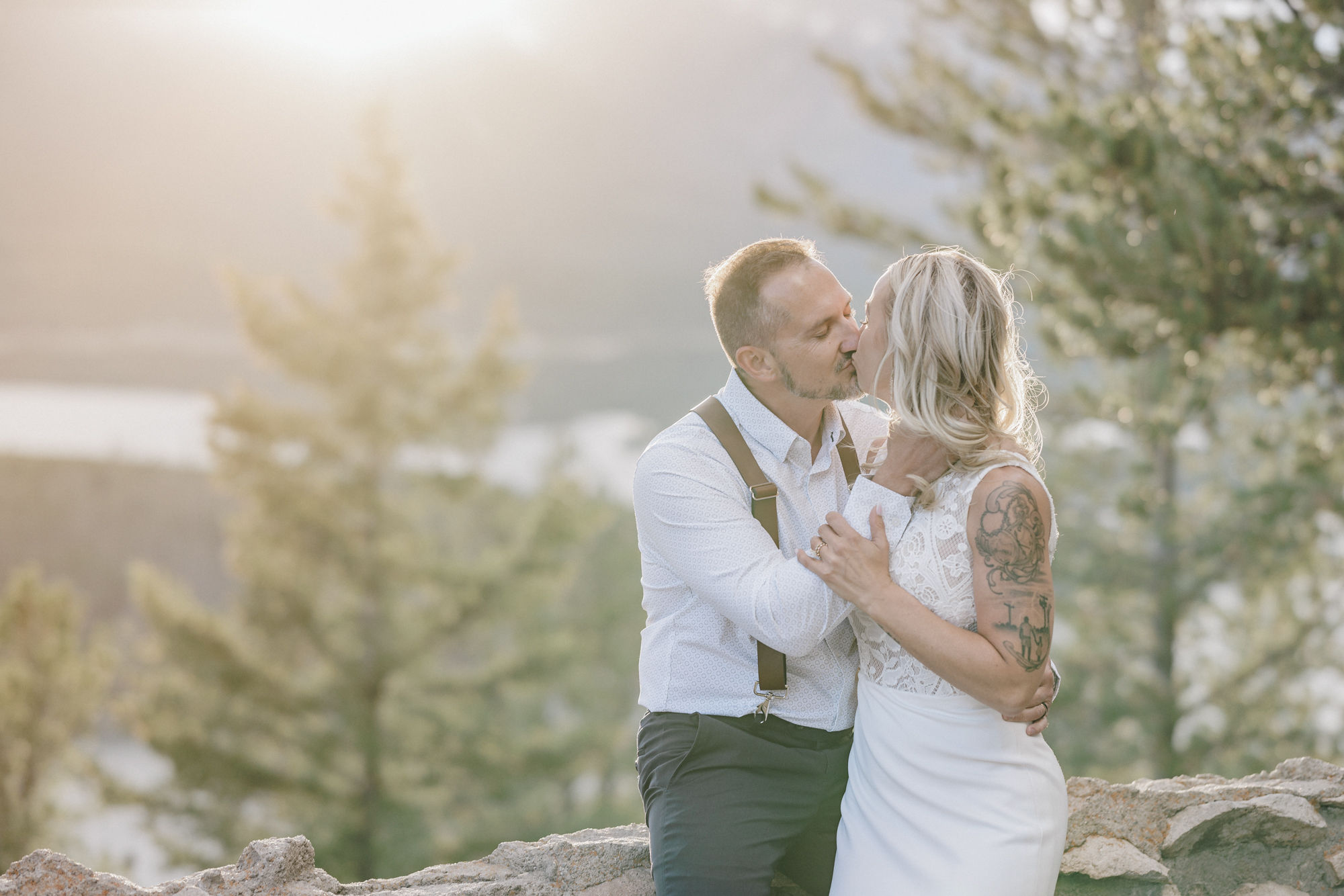 bride and groom kiss while sitting on rock during elopement photos