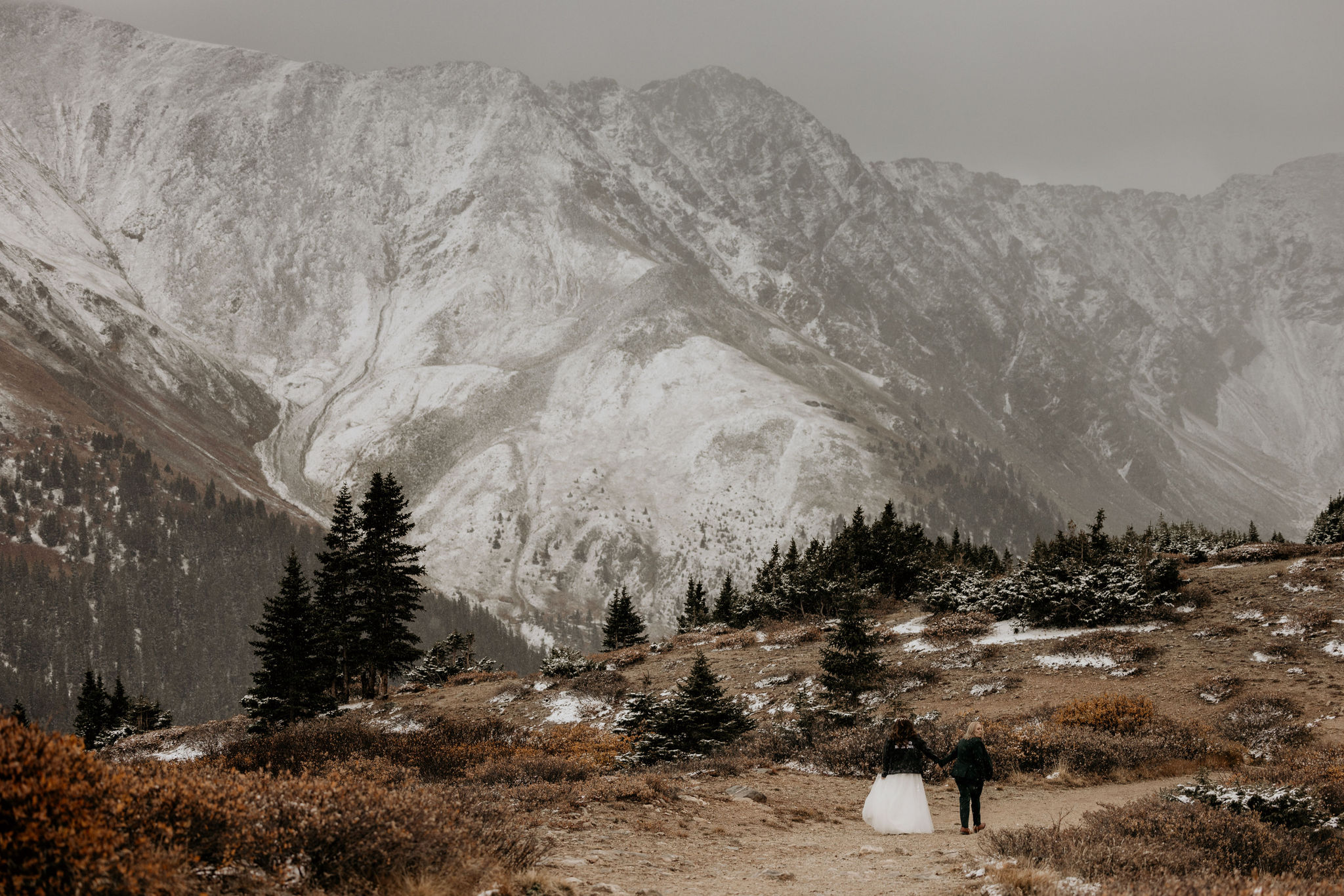 LGBTQ+ couple walks along mountain trail during colorado elopement