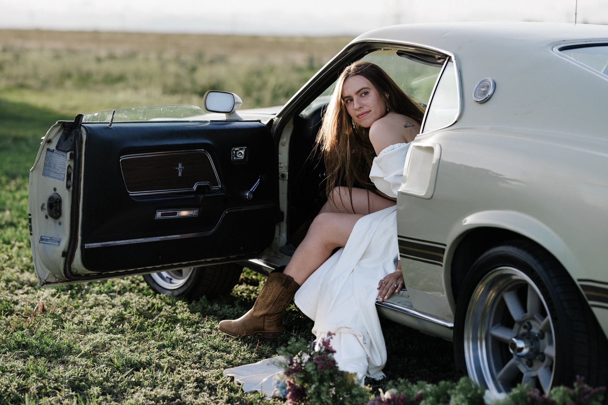 bride sits in drivers seat of vintage car