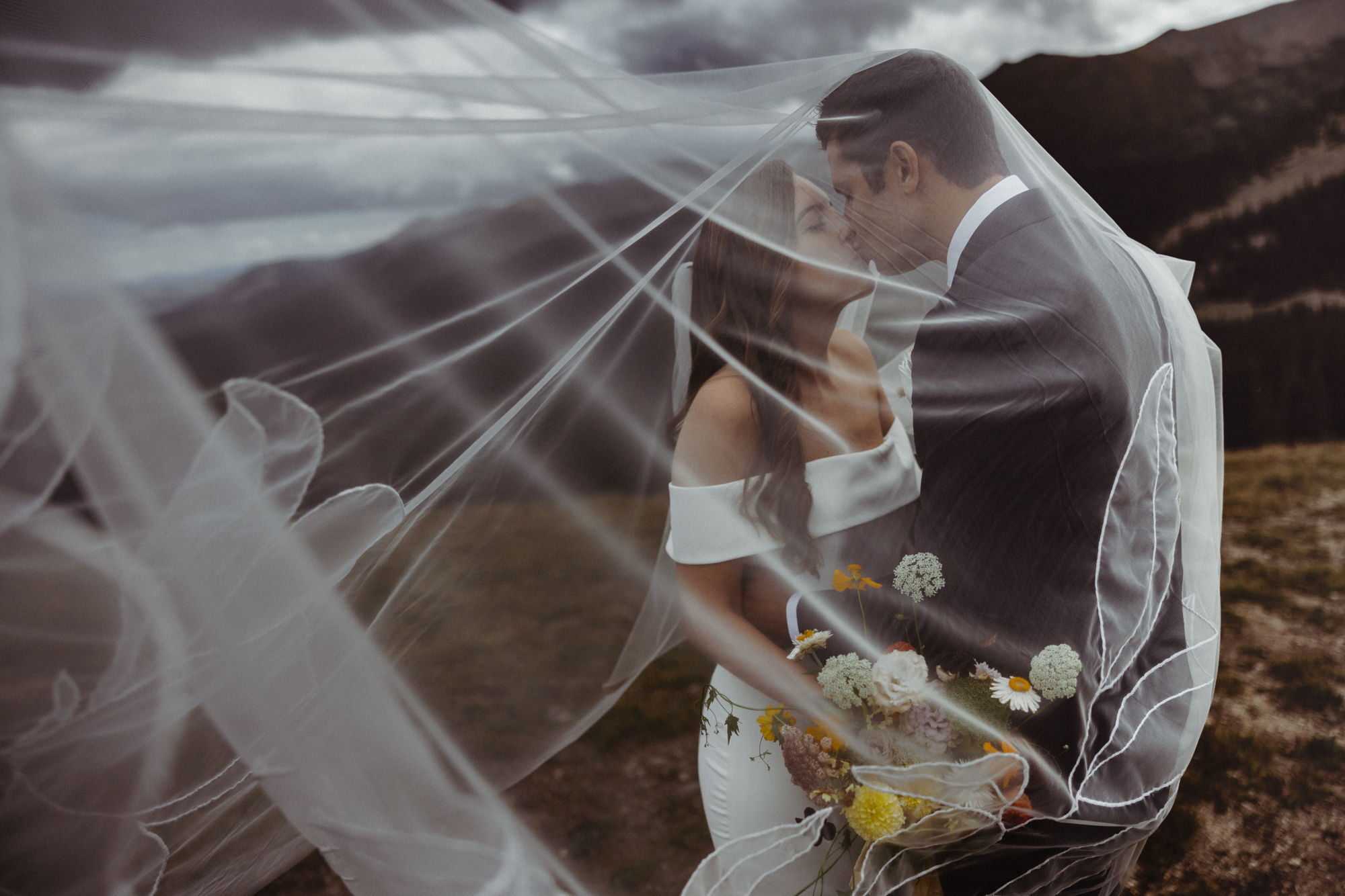 bride and groom kiss under brides veil during wedding photos