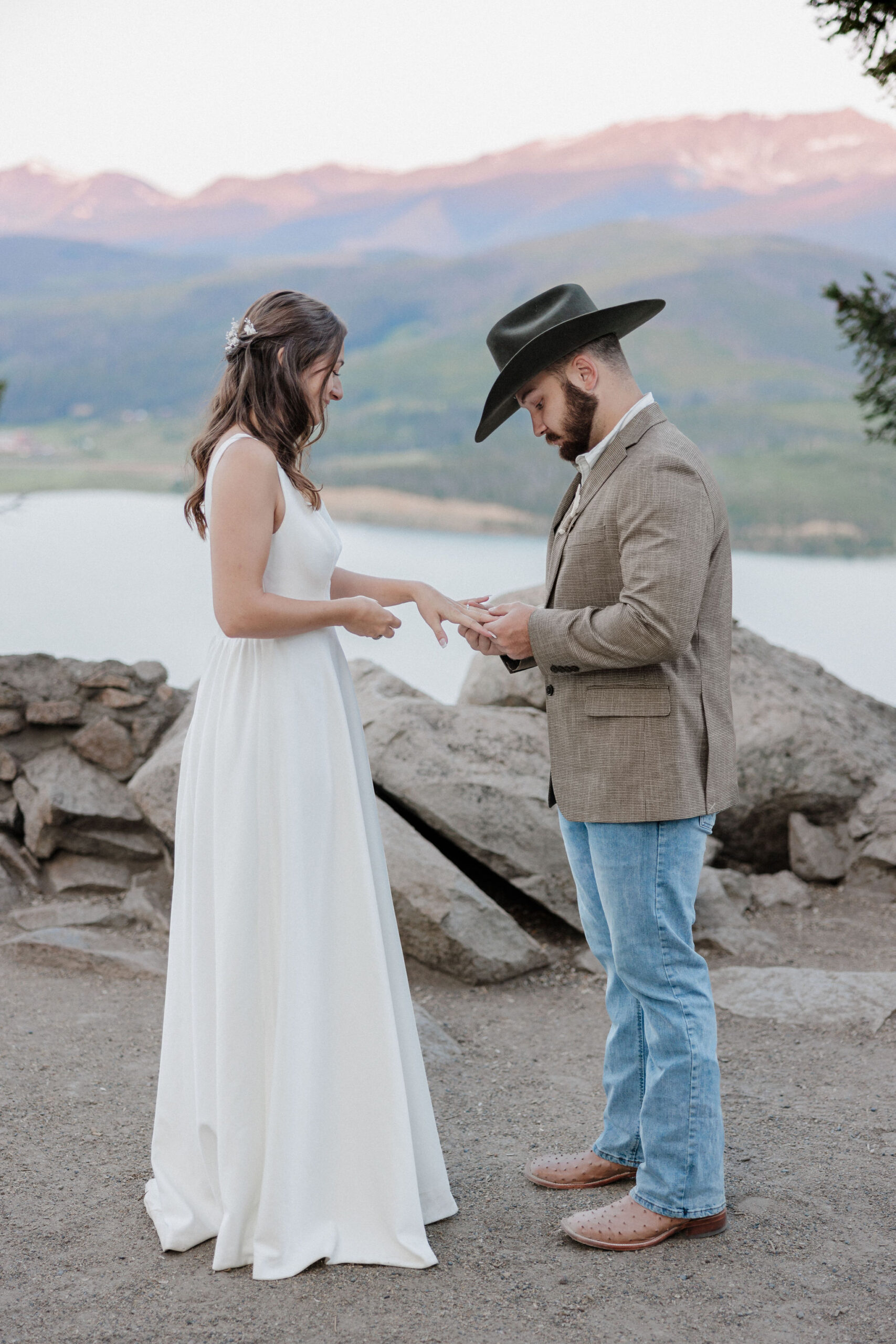 groom puts ring on brides hand during sunrise elopement ceremony in breckenridge