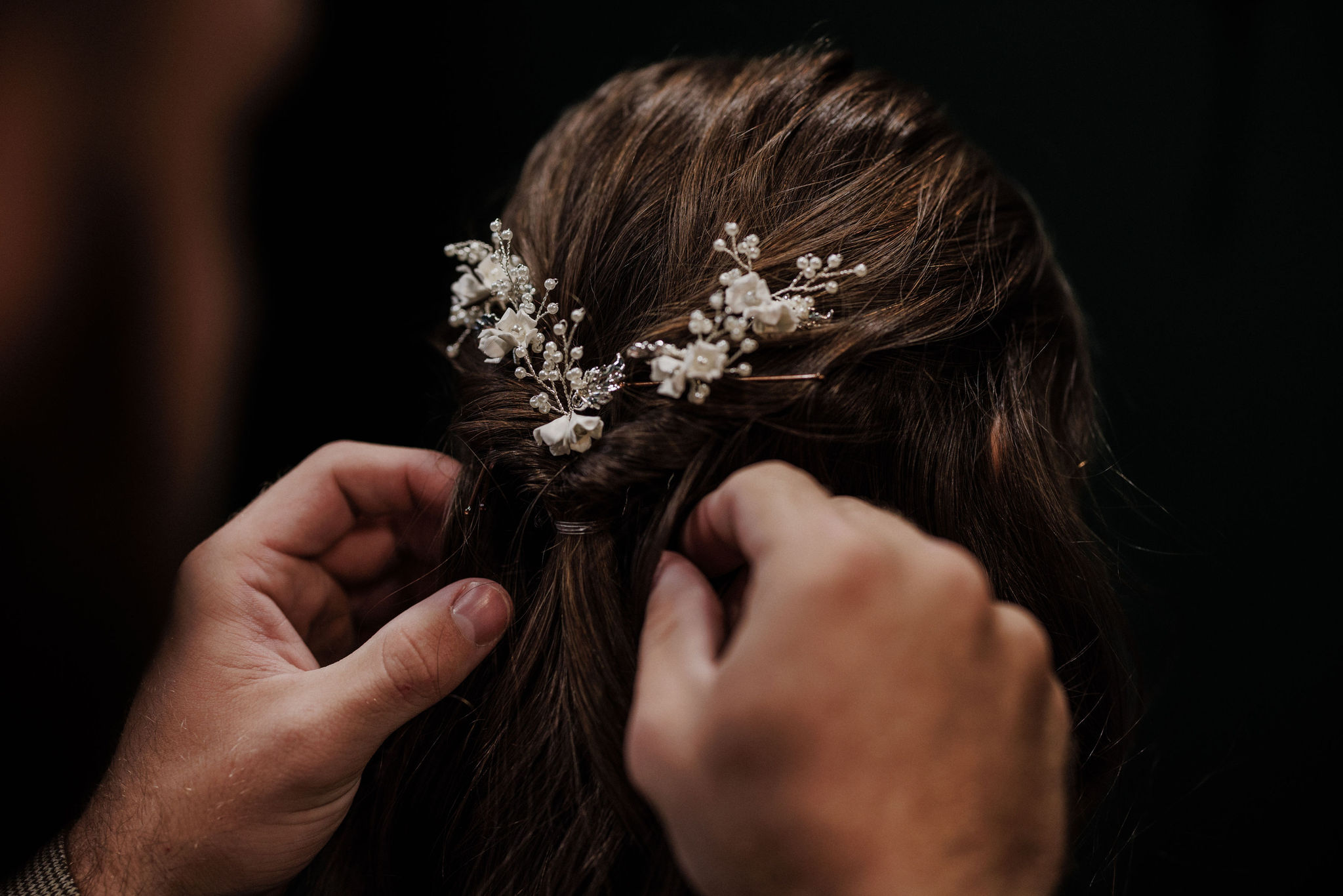 groom helps bride put her hair piece in during getting ready photos