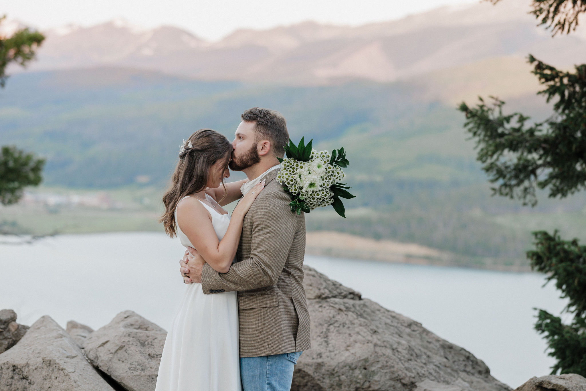 groom kisses brides head at sapphire point overlook after sunrise elopement ceremony