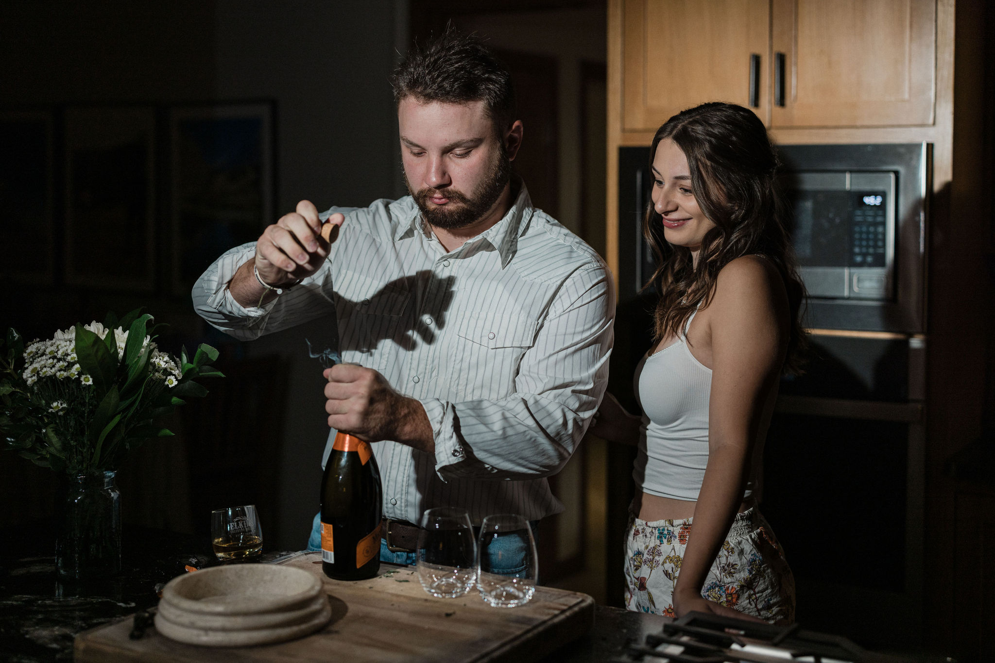 bride and groom pop champagne to make getting ready mimosas before elopement ceremony