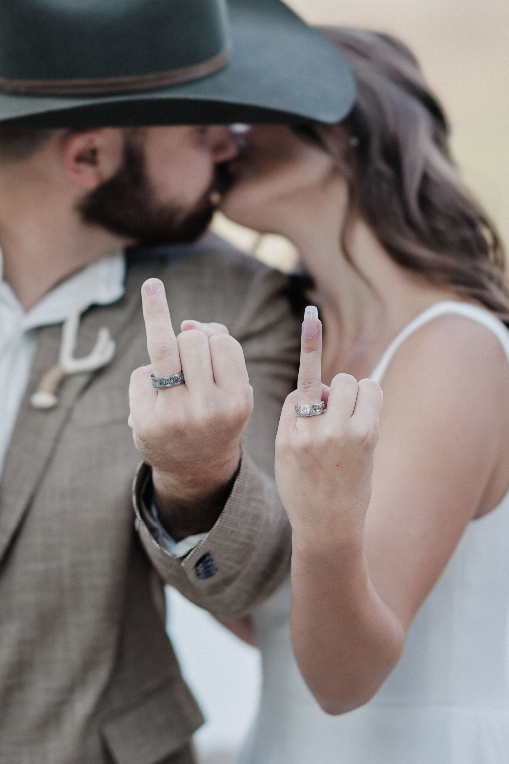 bride and groom kiss and put up their ring fingers