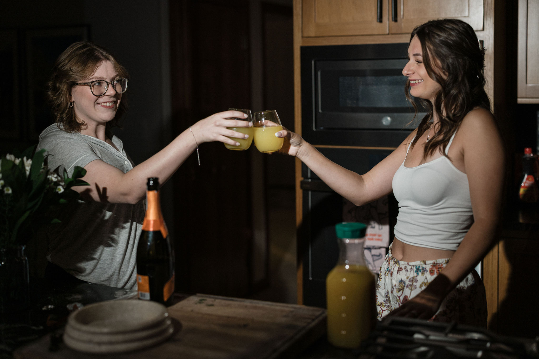 bride and friend cheers mimosas while getting ready for their elopement