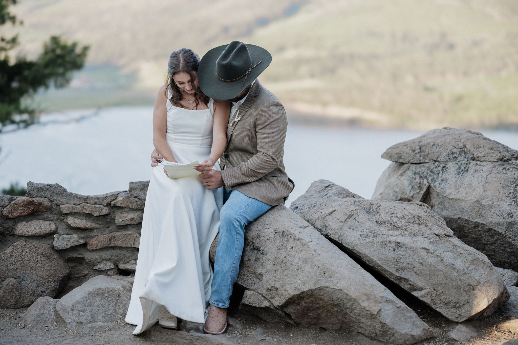 bride and groom sit on rock and sign marriage license