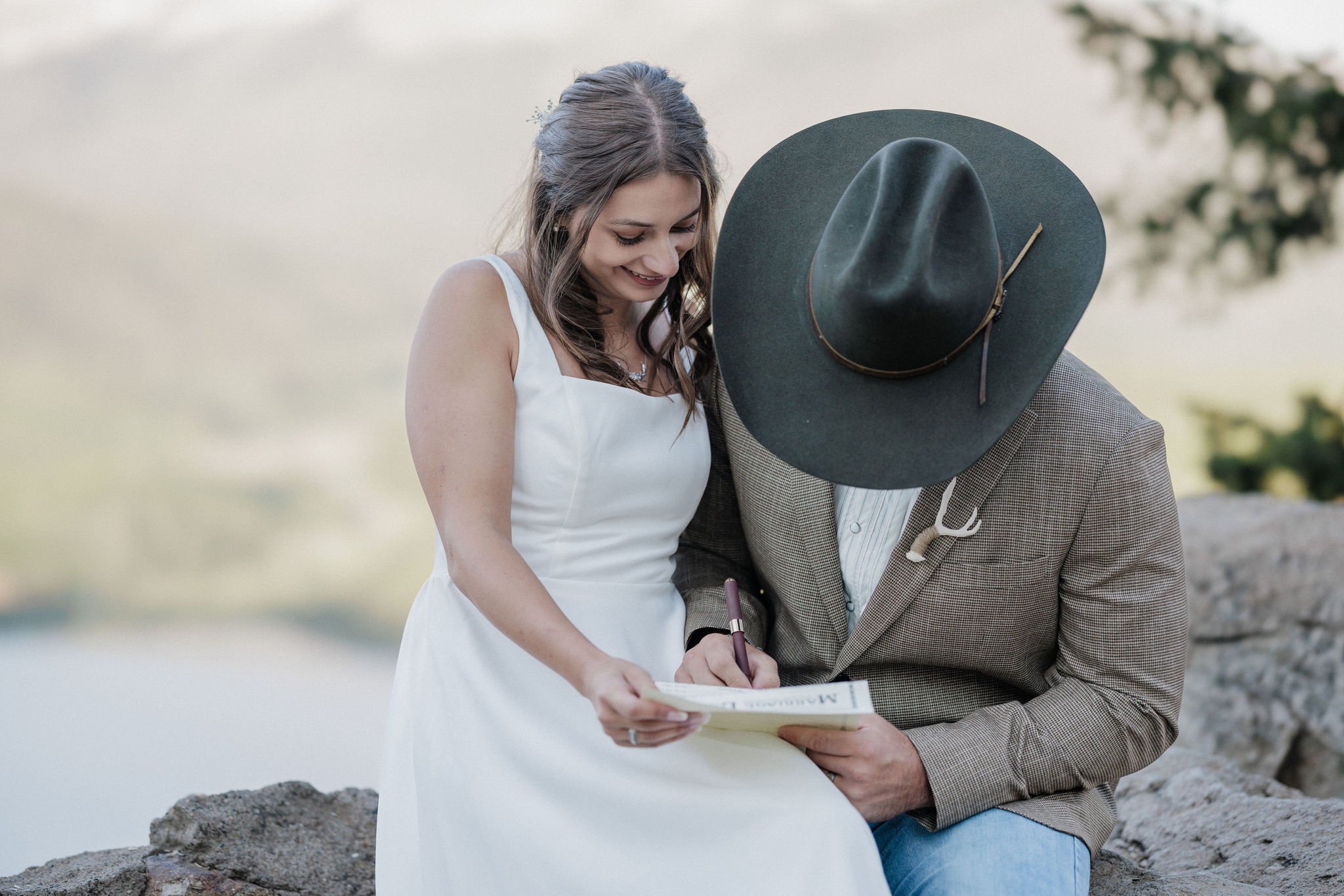 bride and groom smile as they sign colorado marriage license