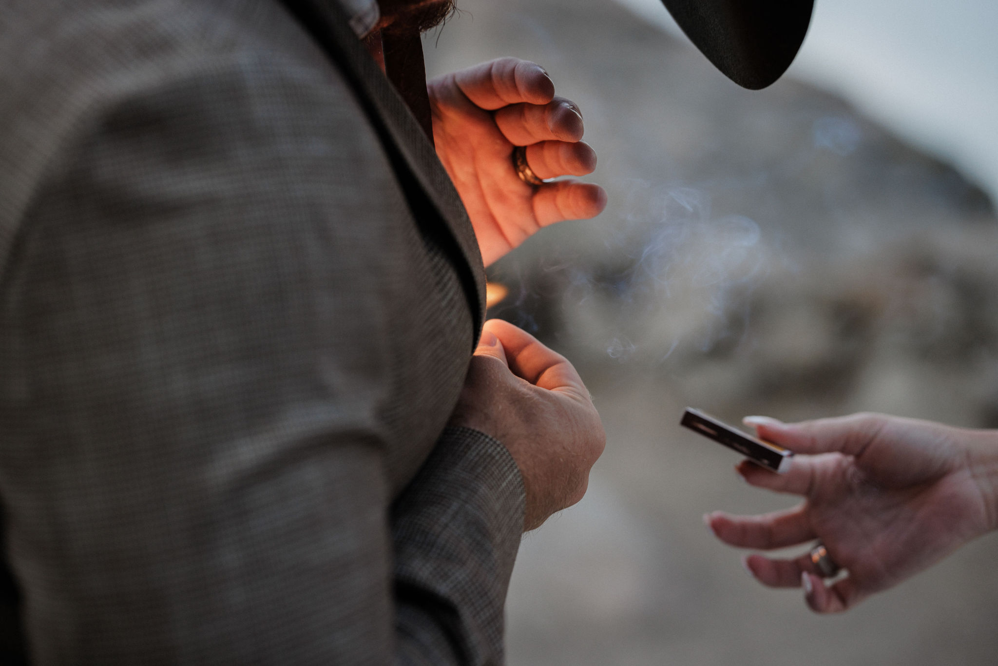 groom lights cigar during wedding photos