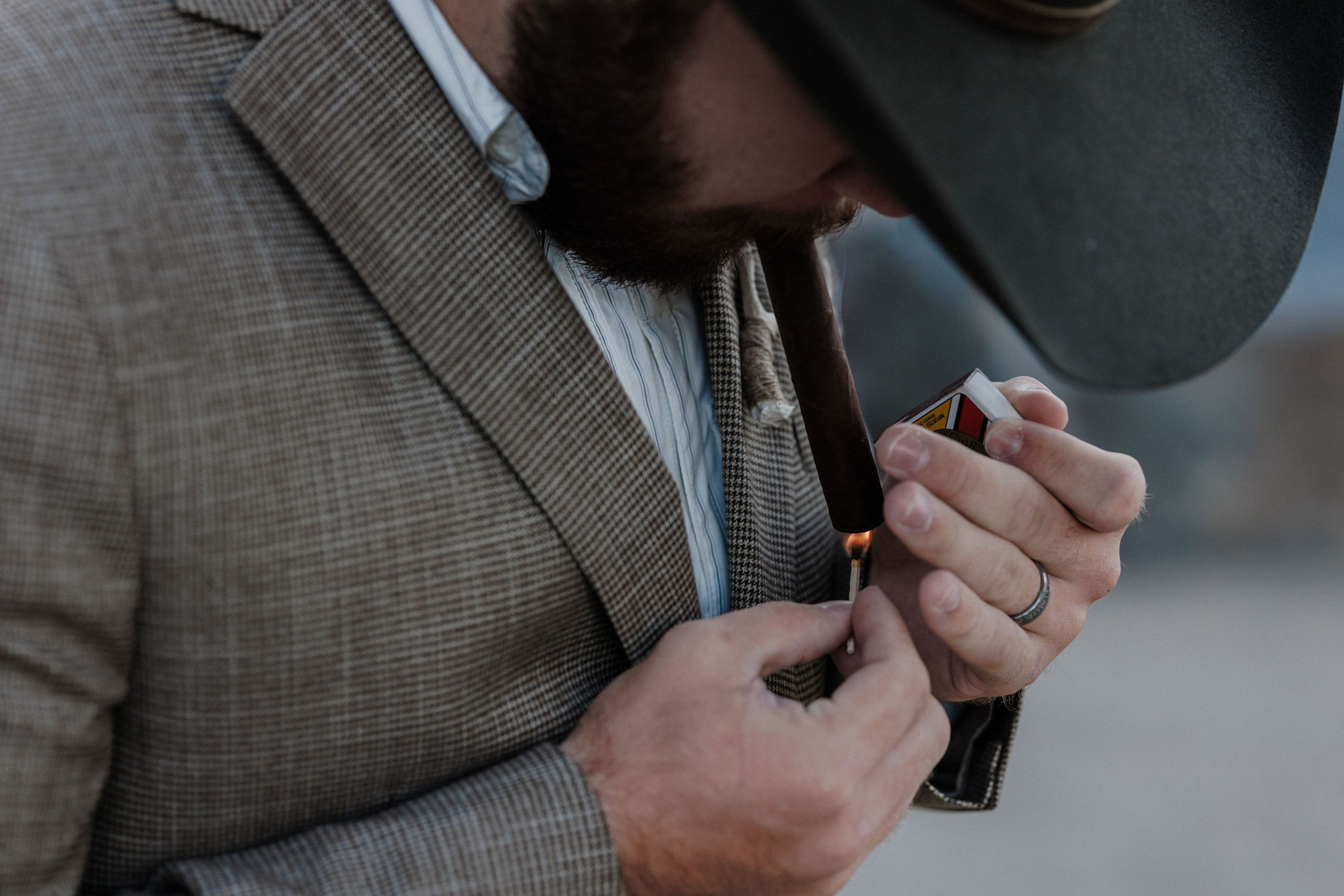 groom lights cigar during wedding photos in their sunrise elopement