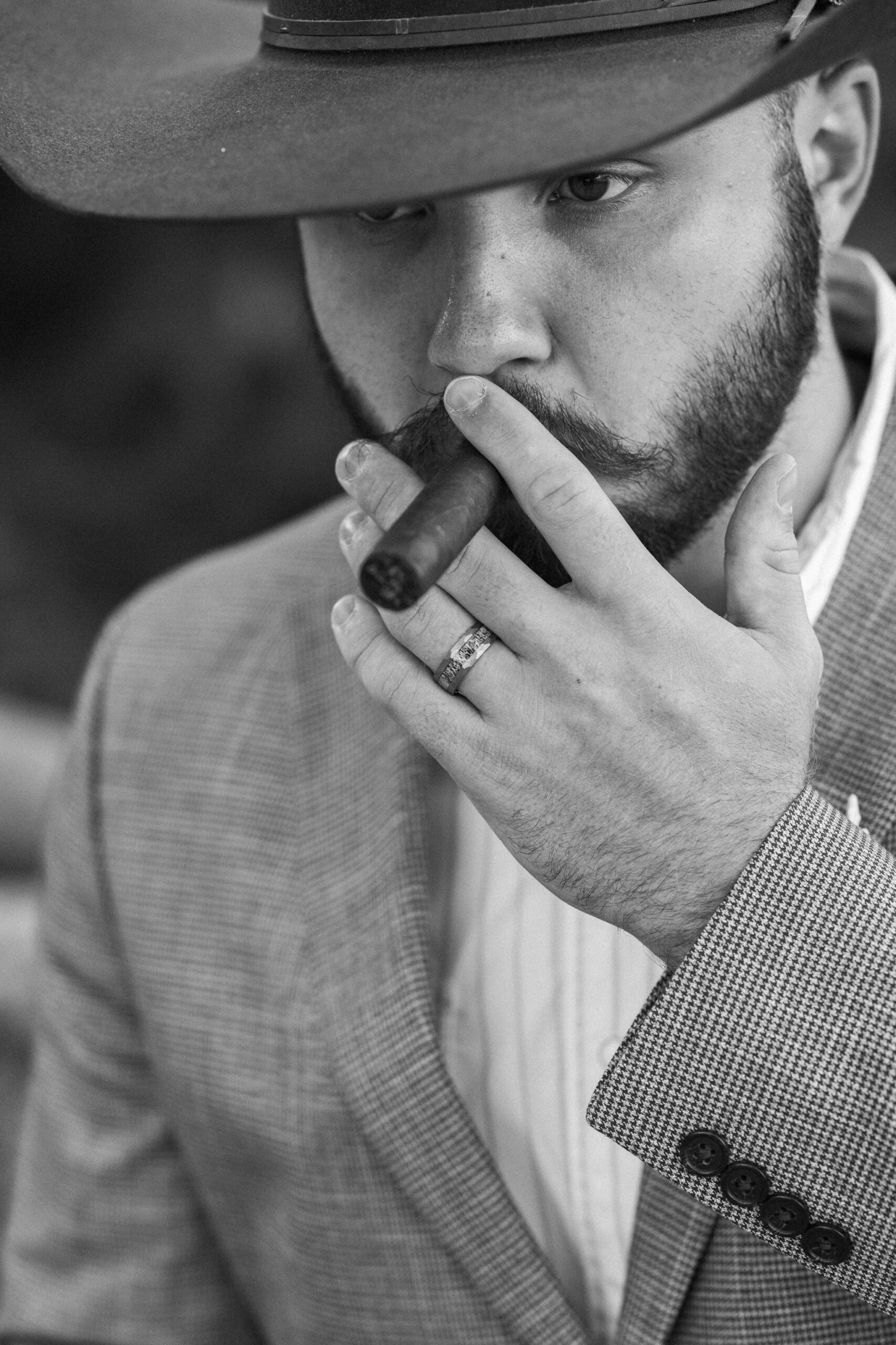 groom smokes cigar during wedding photos