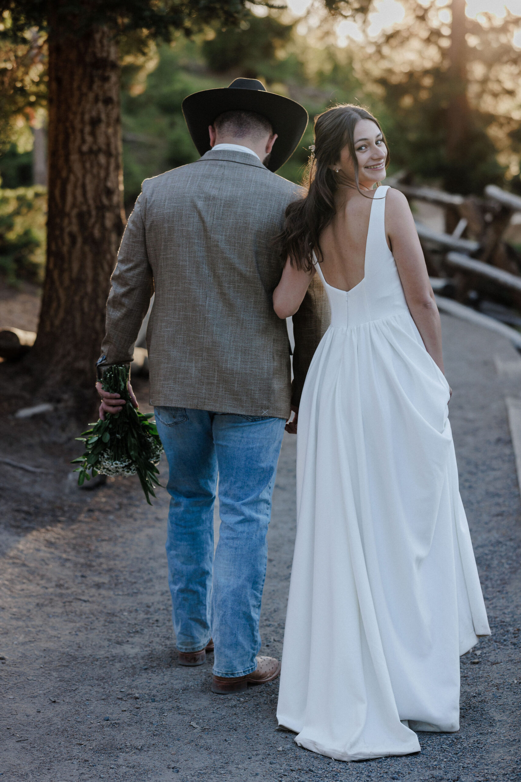 bride and groom walk along trail during elopement photos in colorado