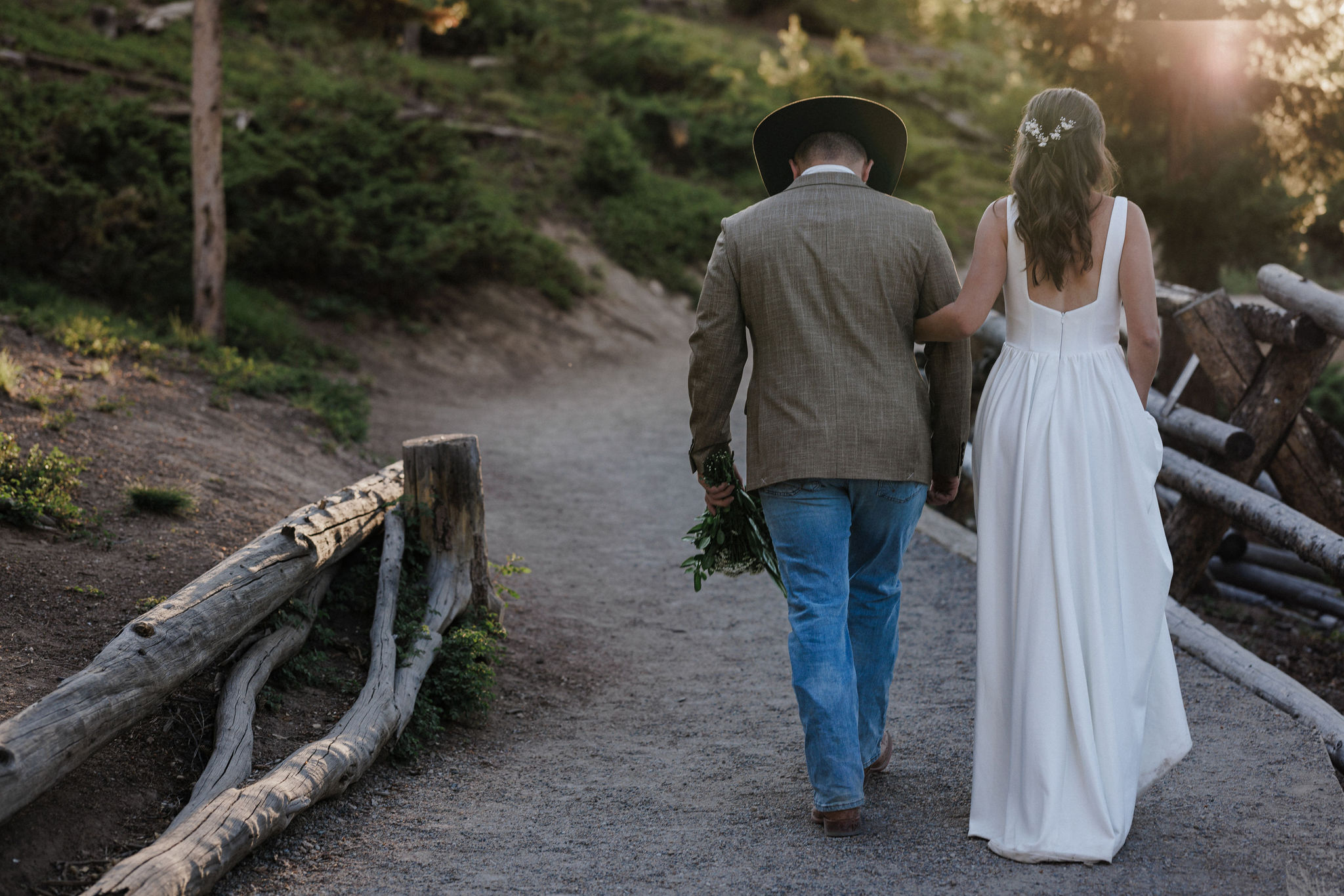 bride and groom walk along path after sunrise elopement ceremony