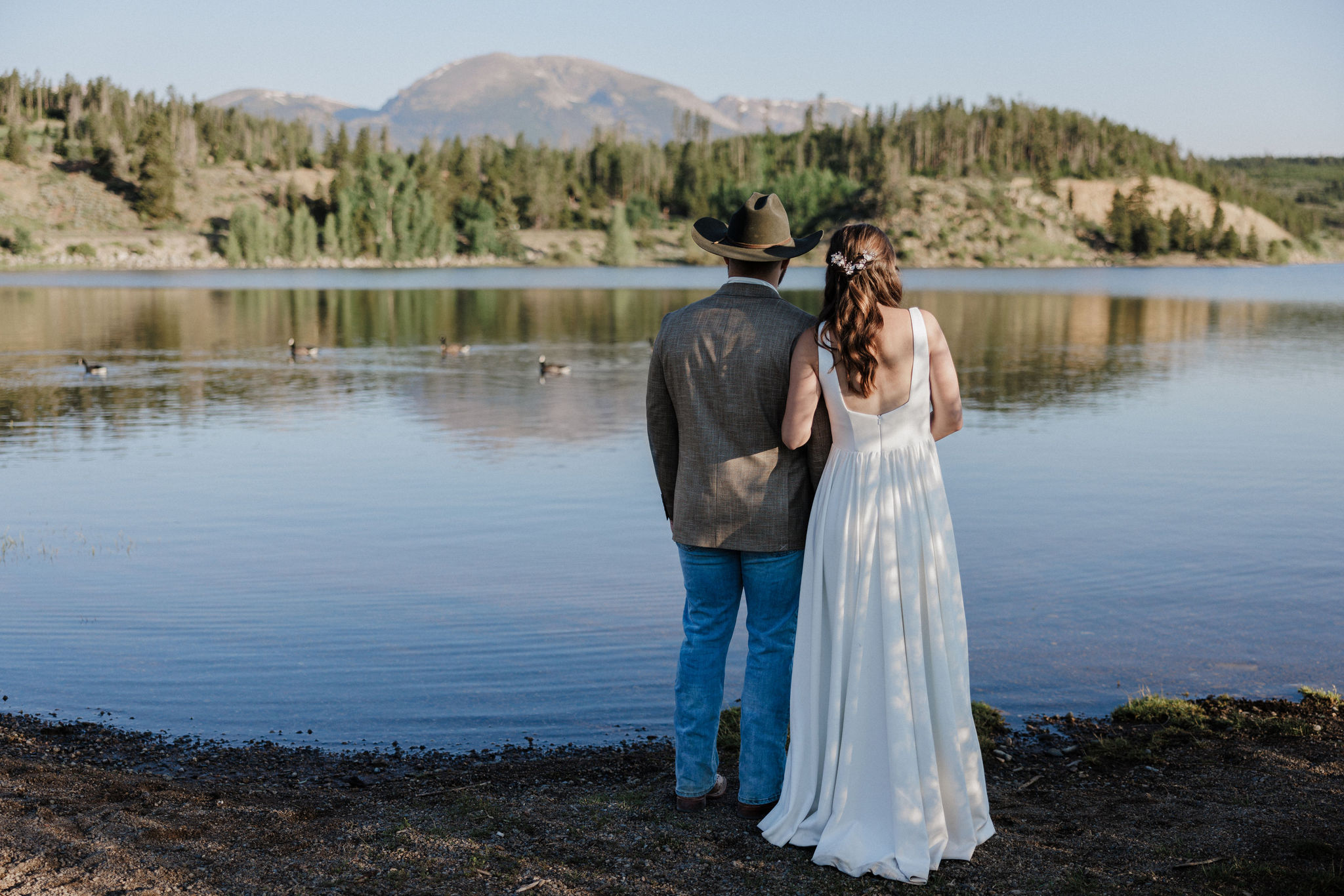 standing on the edge of lake dillon, bride and groom pose for colorado elopement photographer