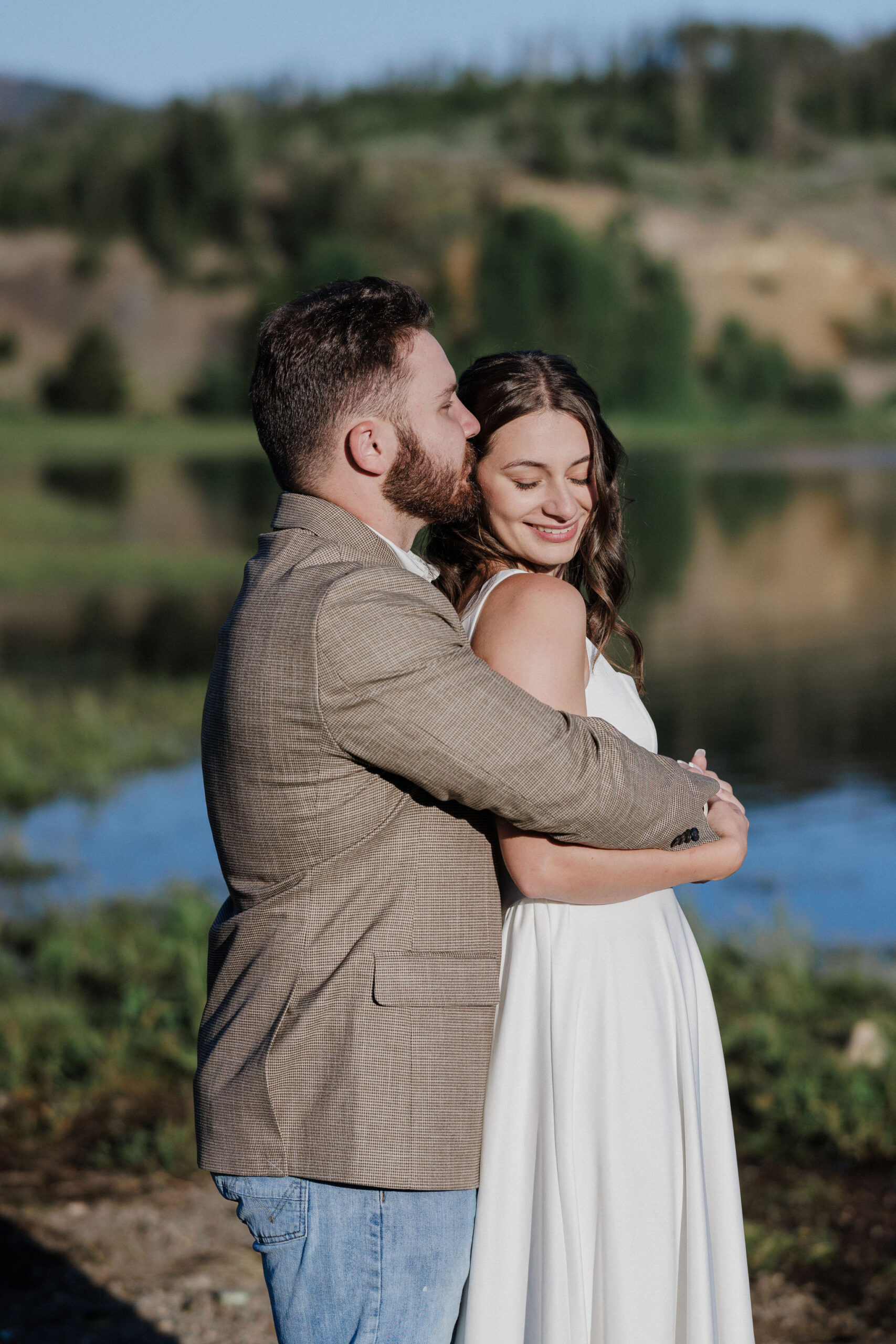 groom grabs bride form behind and gives her a kiss during wedding photos