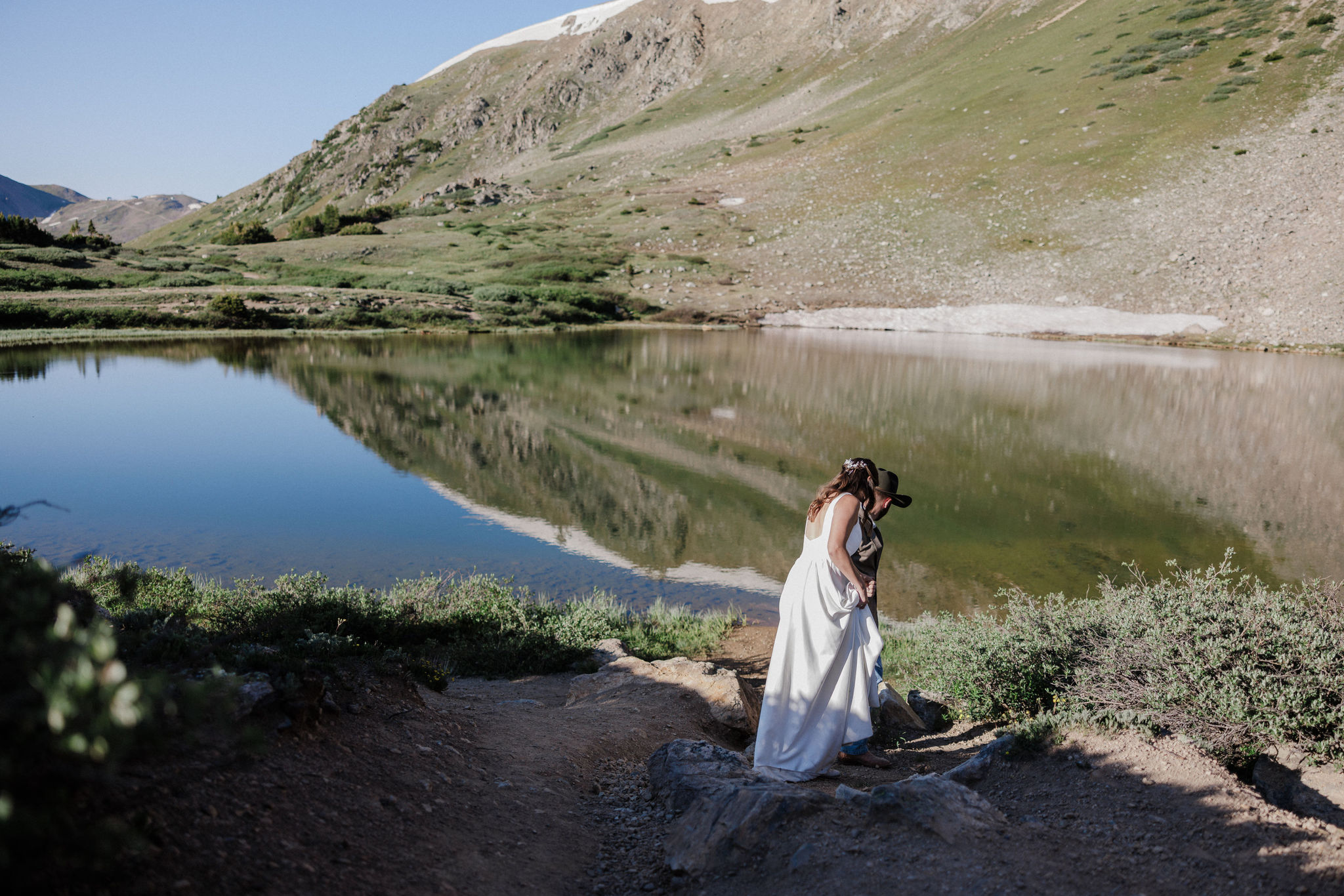 bride and groom walk hand in hand beside Lake Dillon in Colorado during elopement