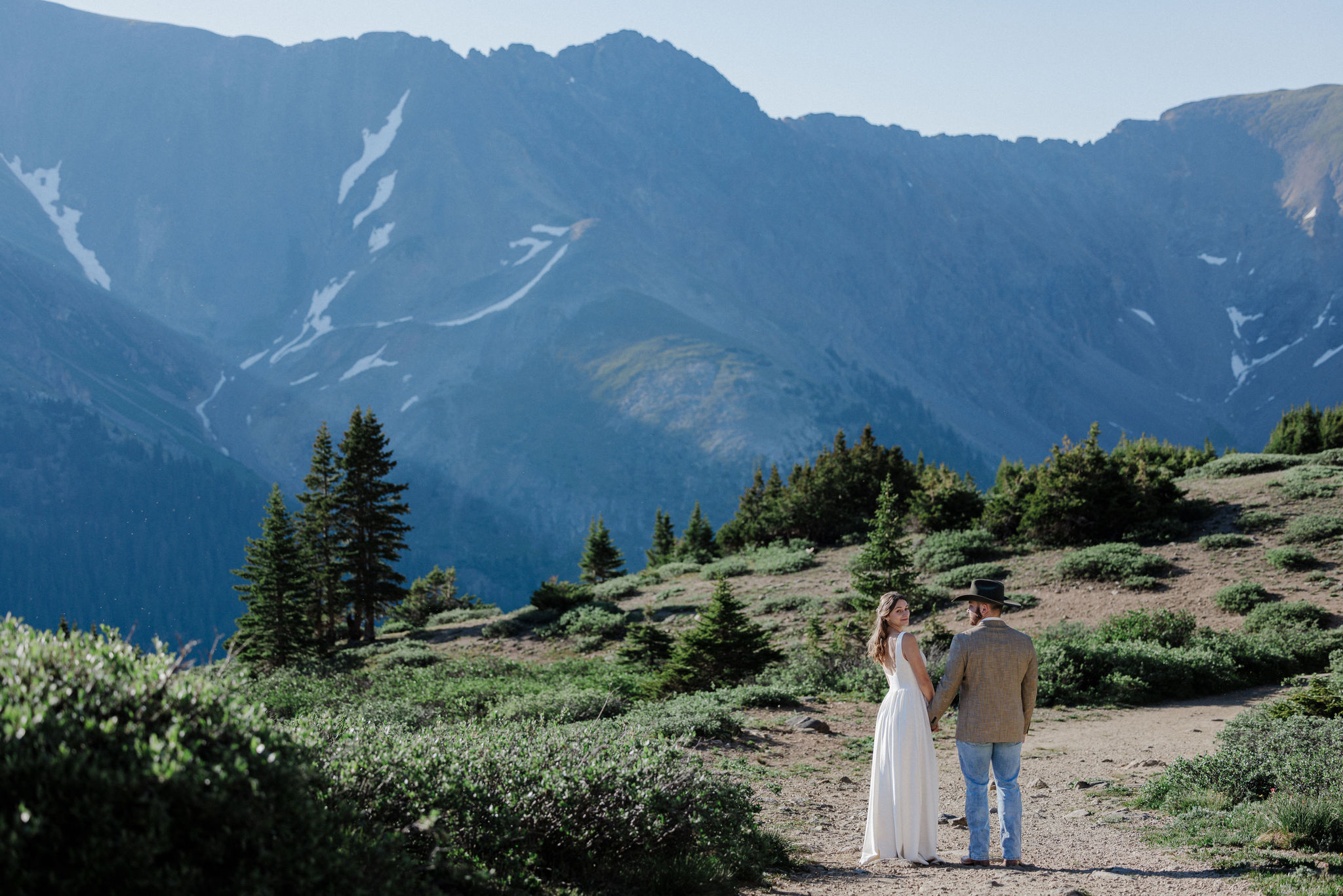 groom and bride walk along dramatic mountain peaks for sunrise elopement