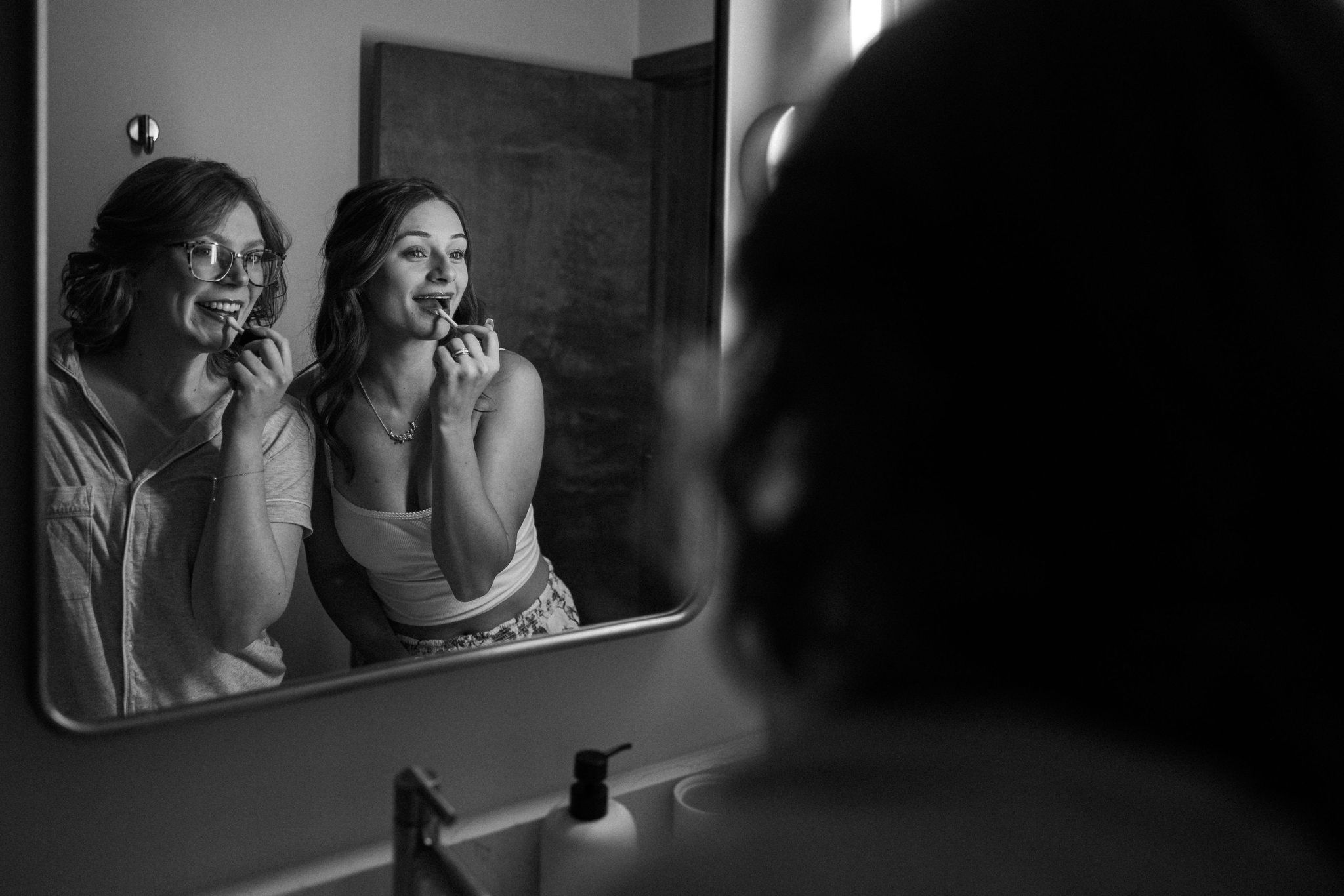 bride and friend put lipgloss on while getting ready for her intimate elopement