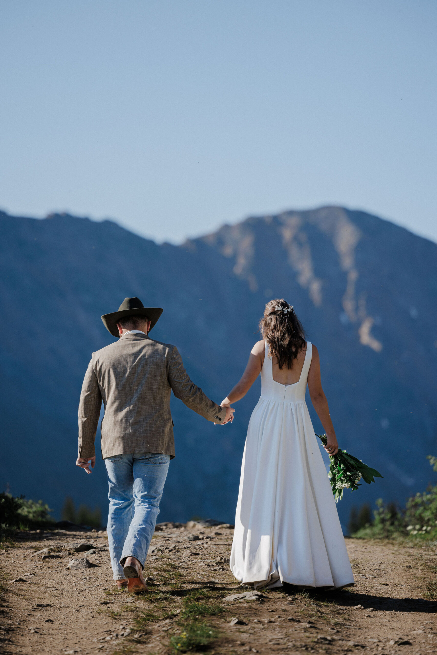 bride and groom walk along mountain trail during colorado elopement photos