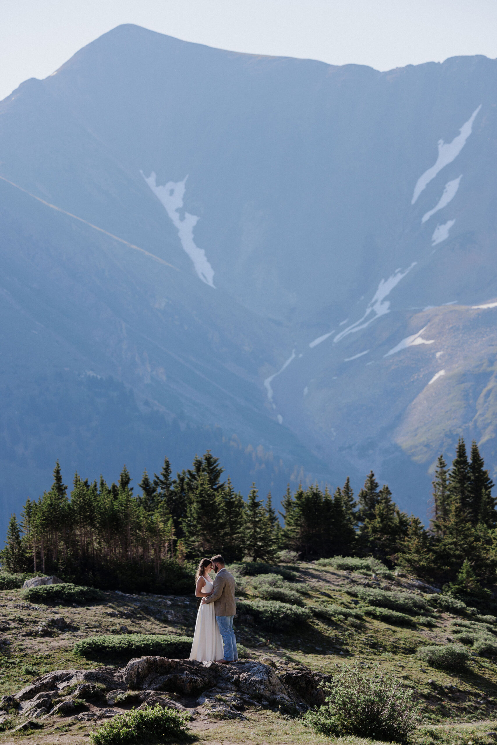 bride and groom stand on rock during elopement photos at Loveland Pass Lake in Colorado