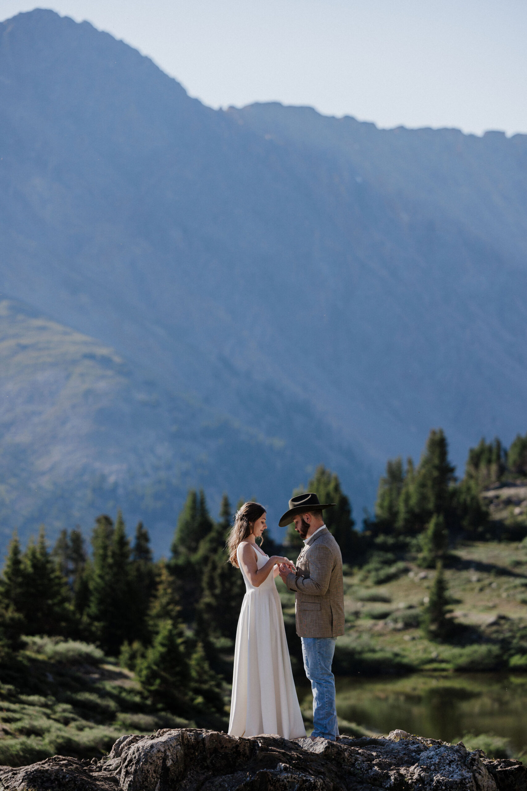 bride and groom hold hands as they stand on rock during sunrise elopement