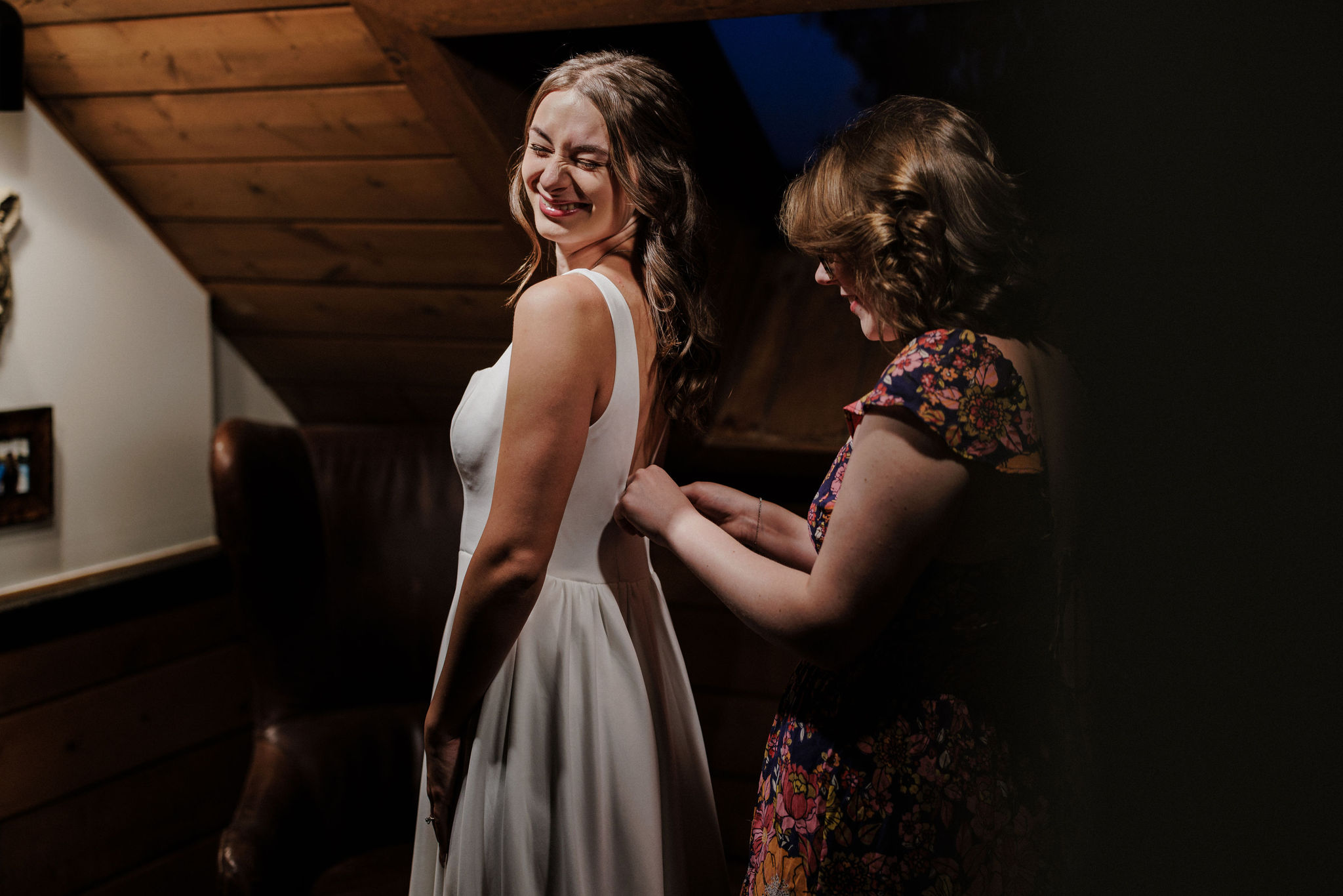 brides friend helps with her wedding dress