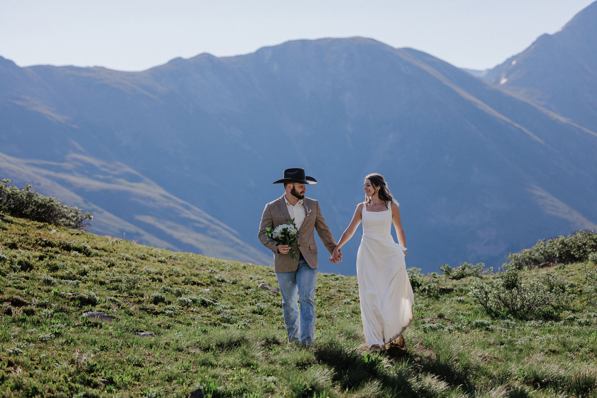 bride and groom hold hands while talking wedding photos