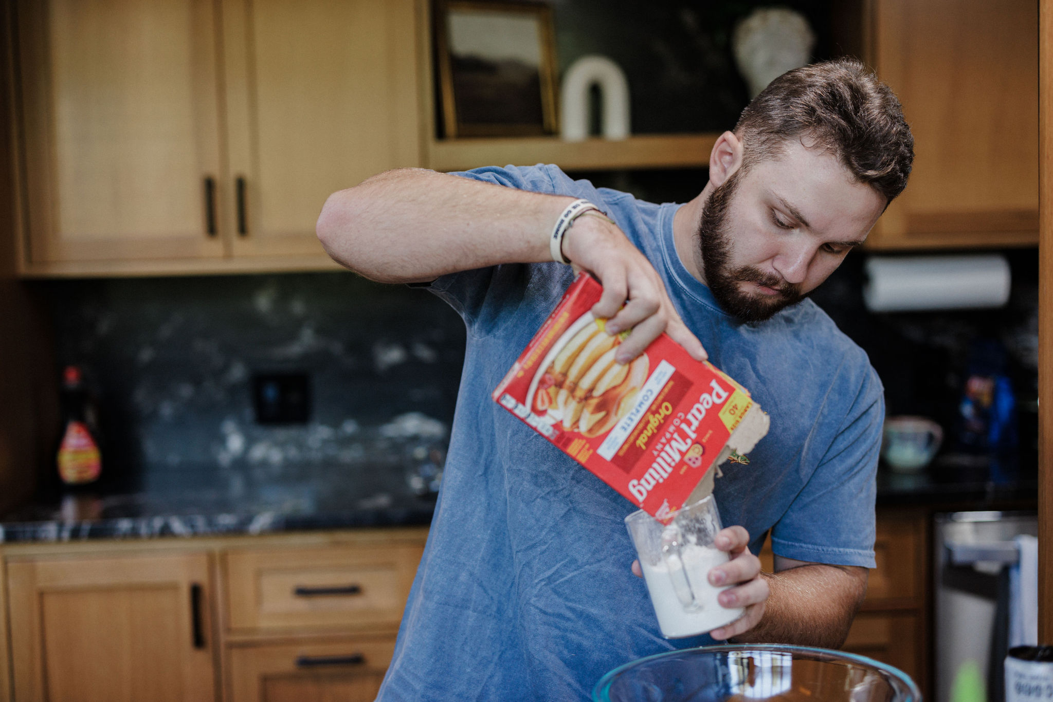 man pours pancake mix into measuring cup while making a post-elopement breakfast