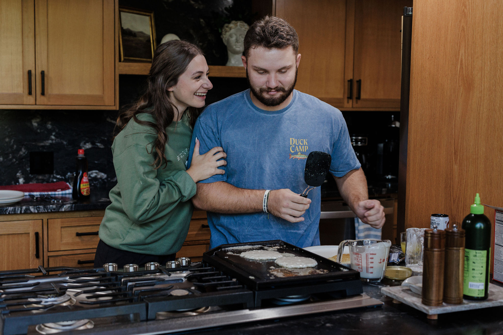 bride grabs grooms arm while they make a pancake breakfast for their elopement