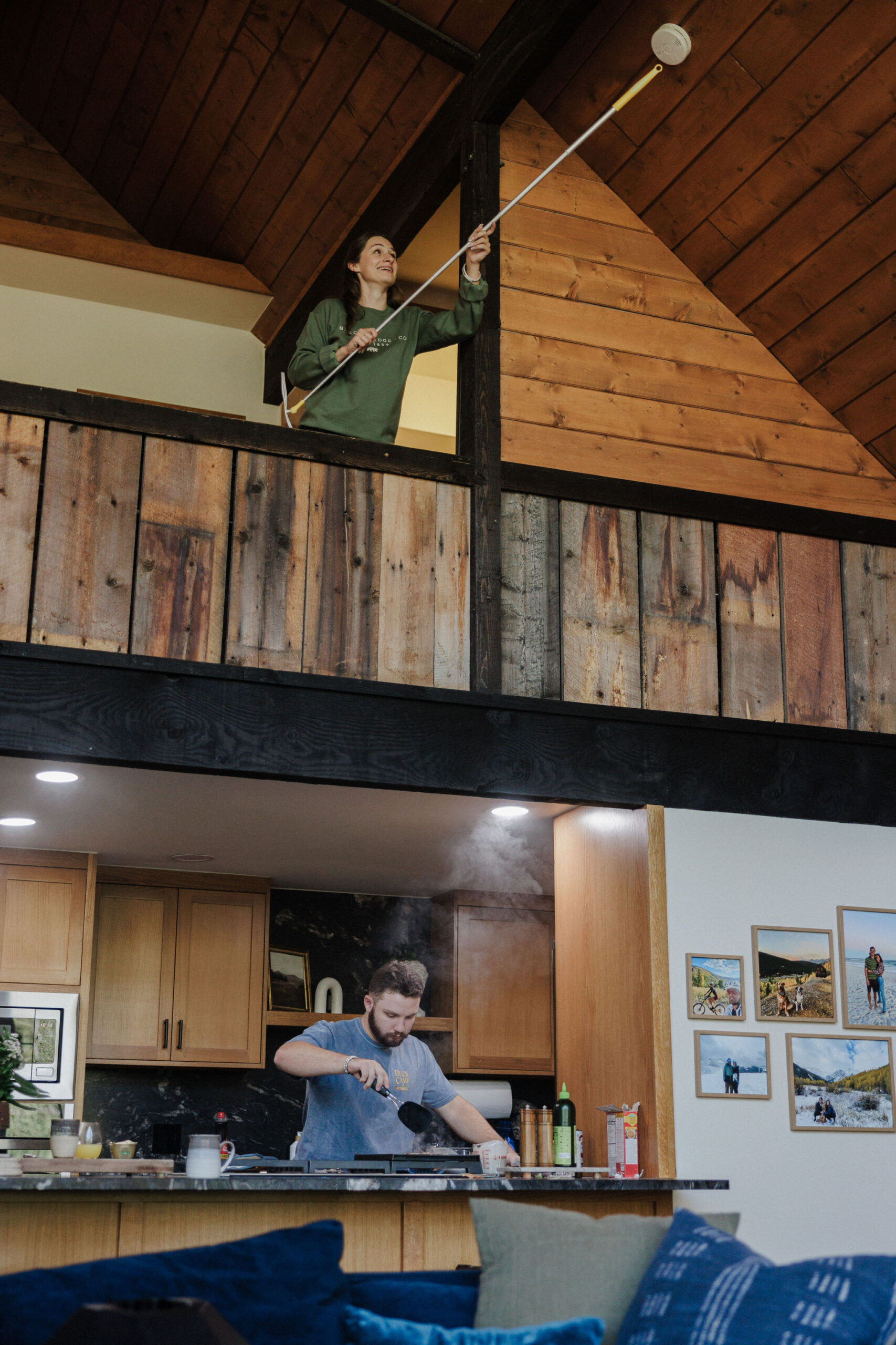 bride turns off smoke detector with broom while groom flips pancakes