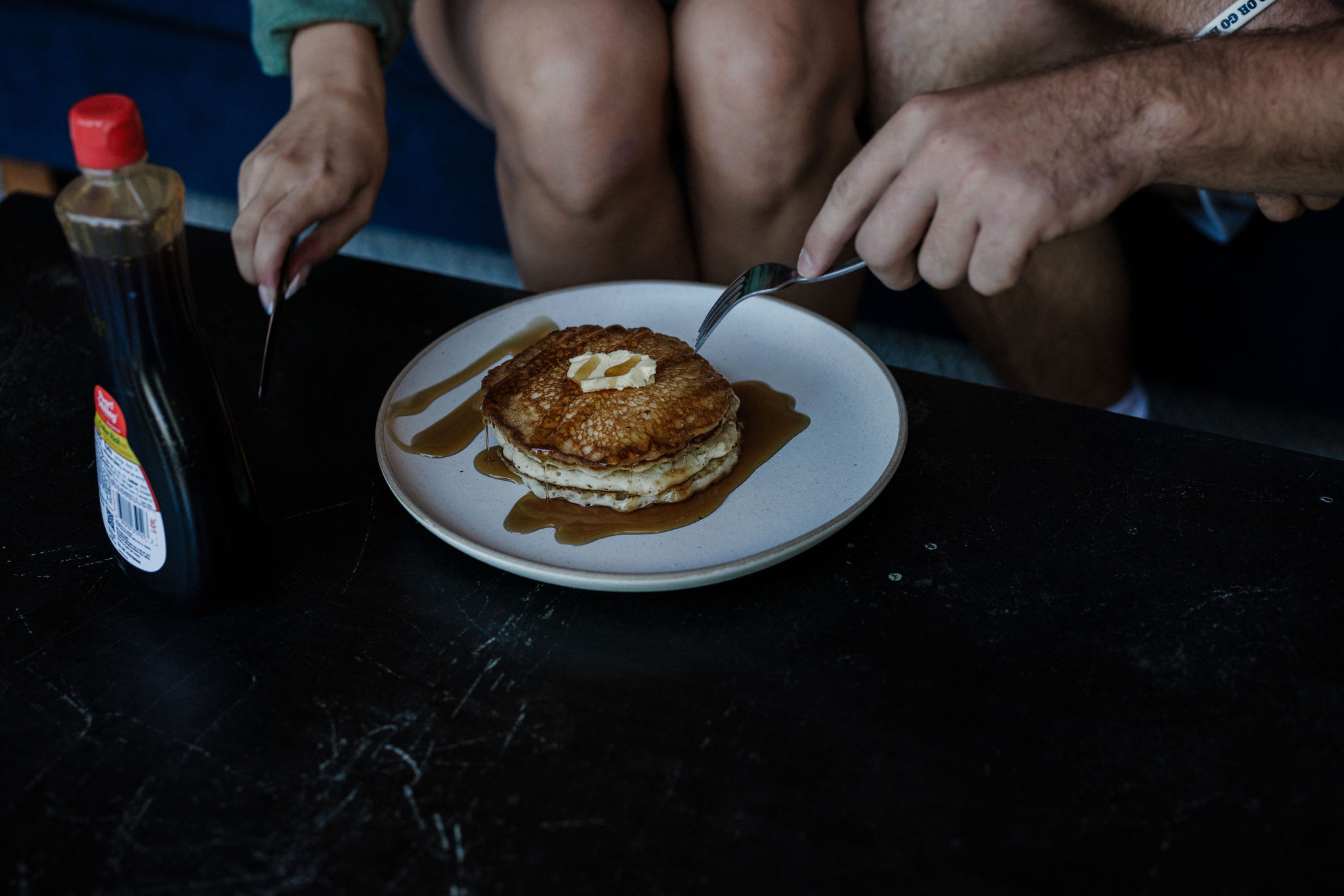 bride and groom cut into stack of pancakes during breakfast after their sunrise elopement ceremony