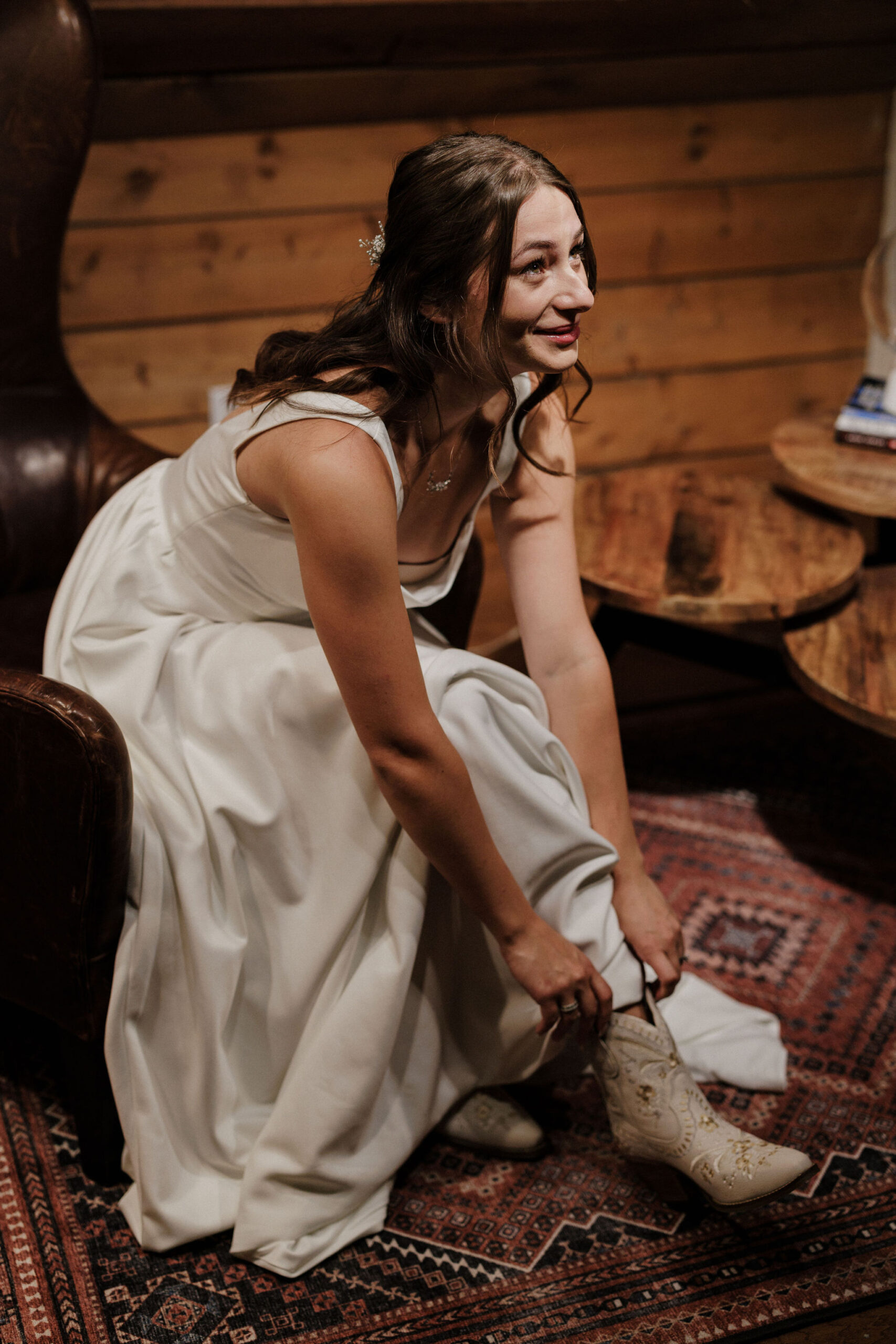 bride puts white cowboy boots on before sunrise elopement