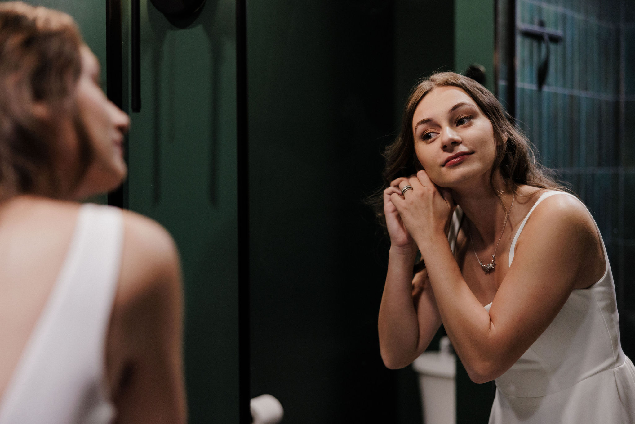 bride puts her earring in while getting ready for her intimate wedding