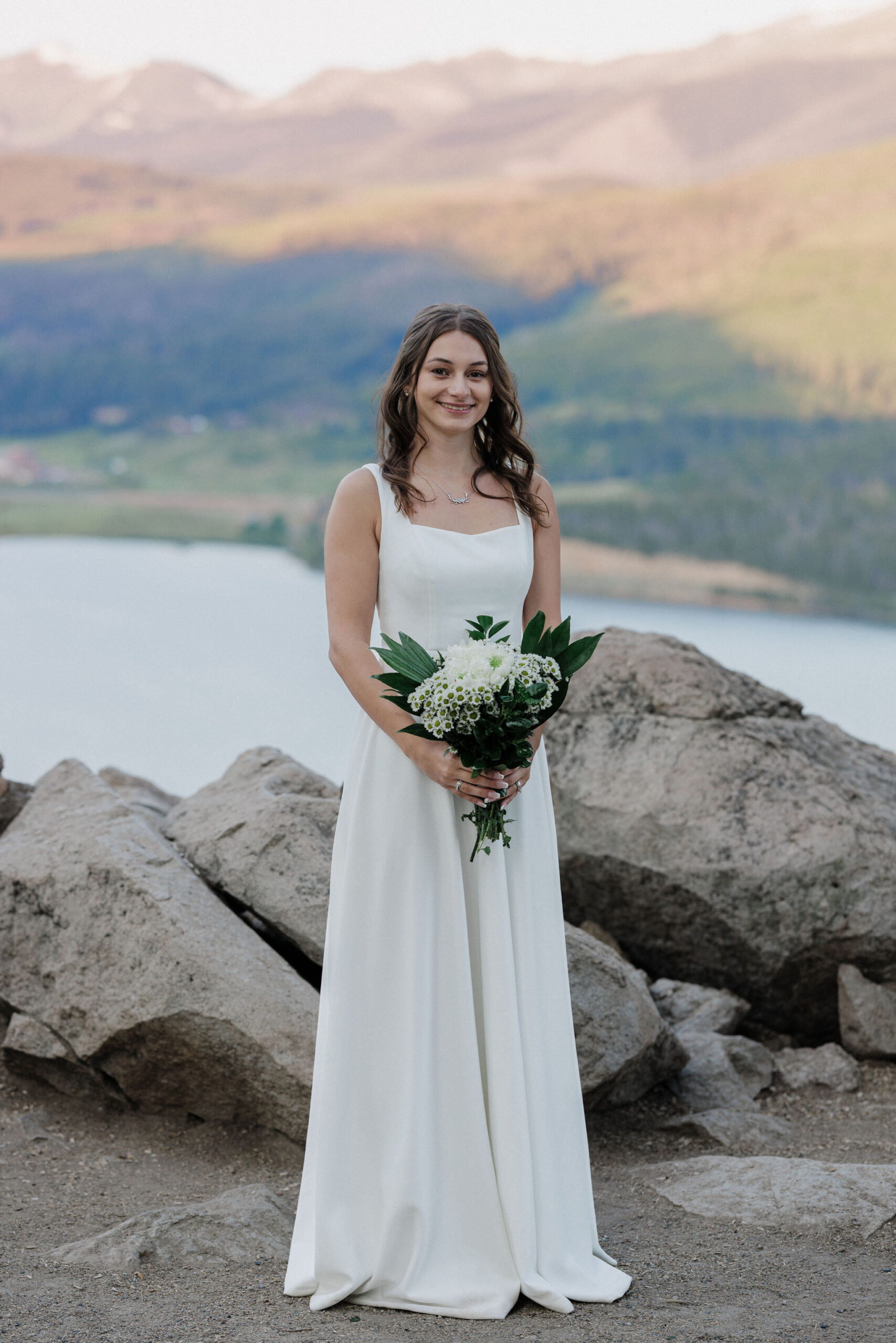 bride stands i nfront of mountains during sunrise elopement