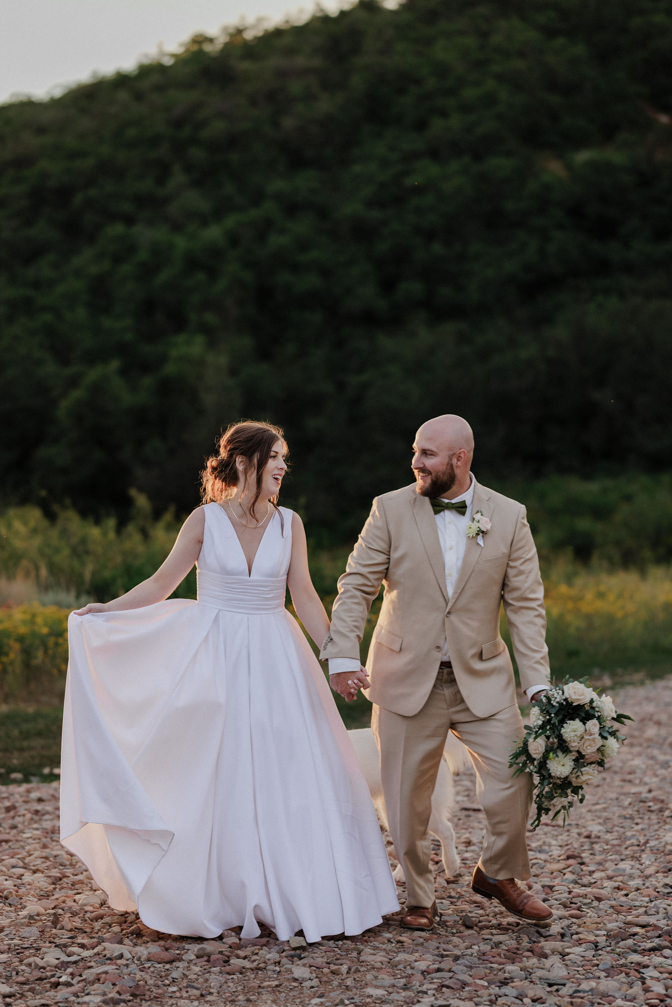 bride and groom hold hands while they walk along road of colorado airbnb