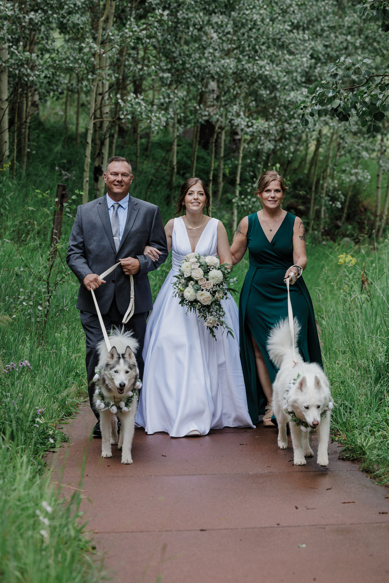 bride walks down the aisle with her parents and dogs at maroon bells amphitheater