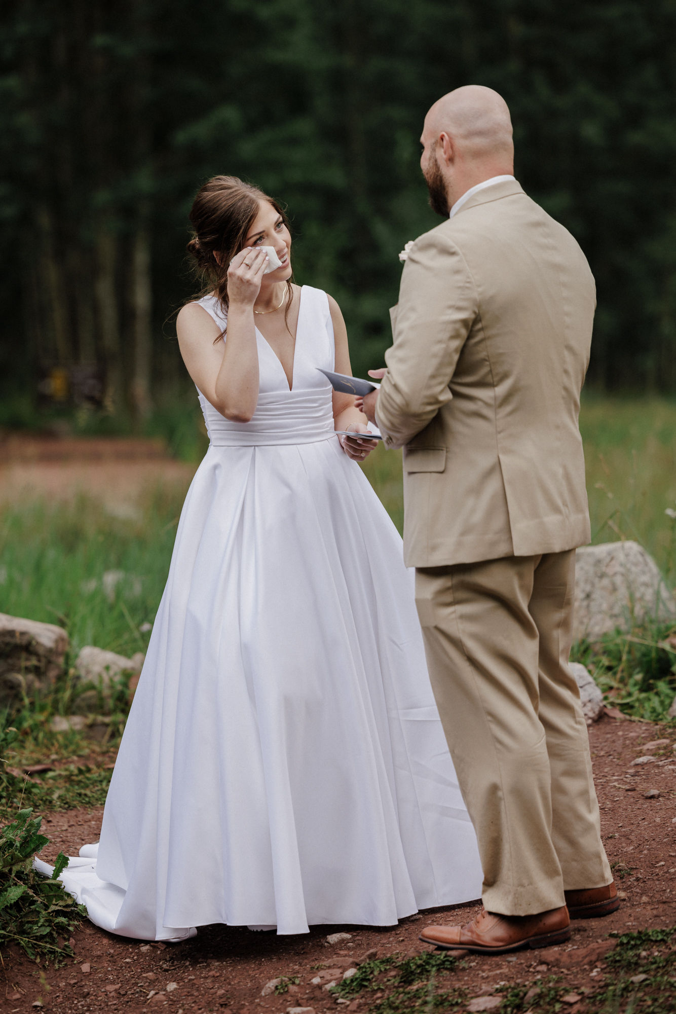 bride wipes eye as groom reads wedding vows in aspen colorado