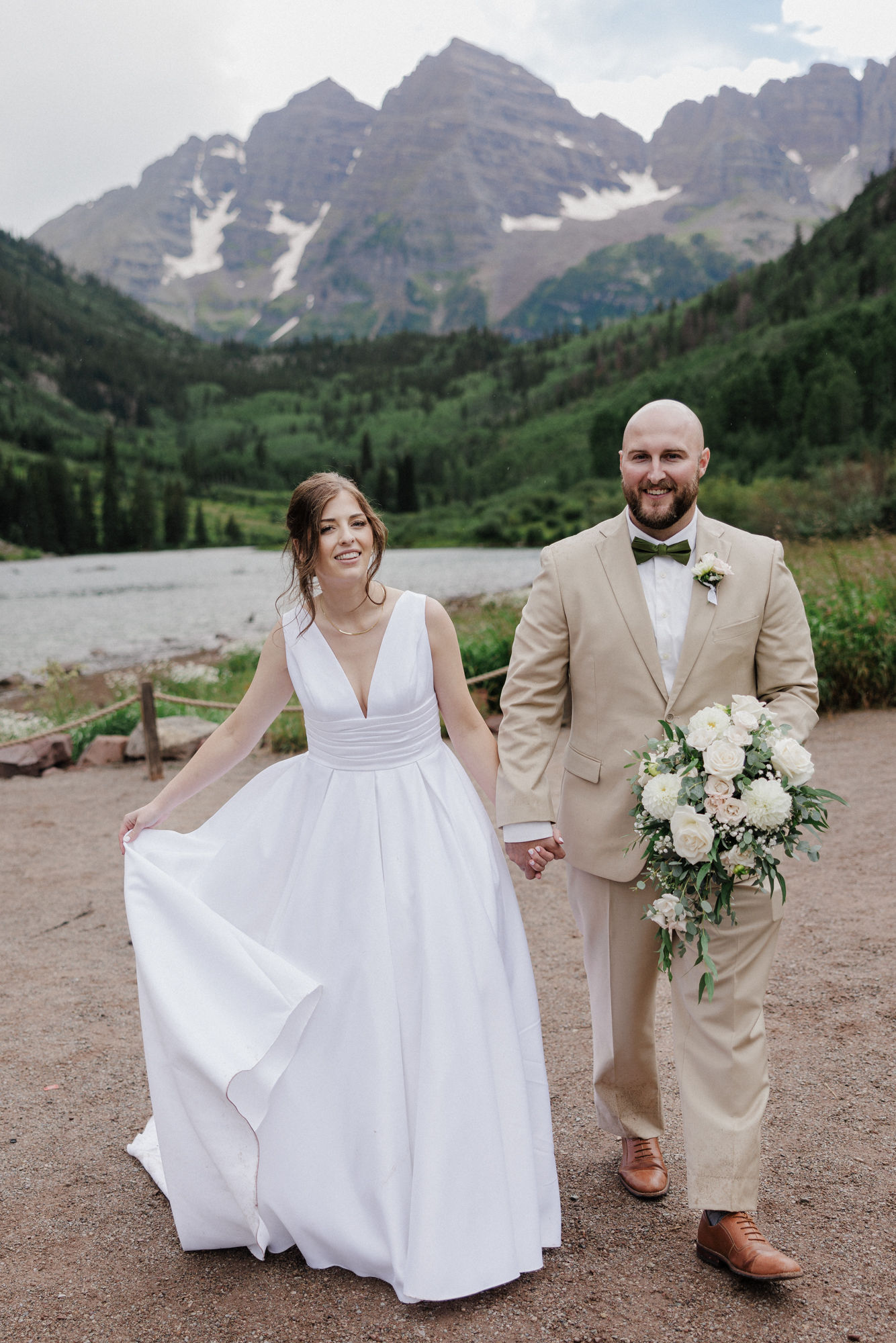 bride and groom hold hands while taking wedding photos at maroon bells in aspen 