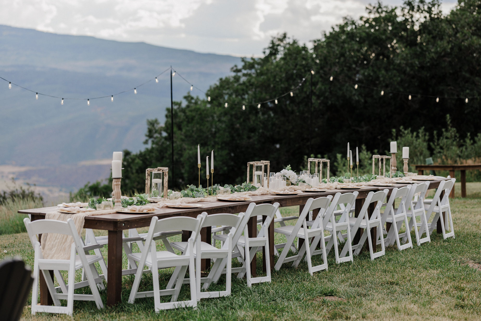 rustic dinner table set up with lights overhead overlooking the colorado mountains