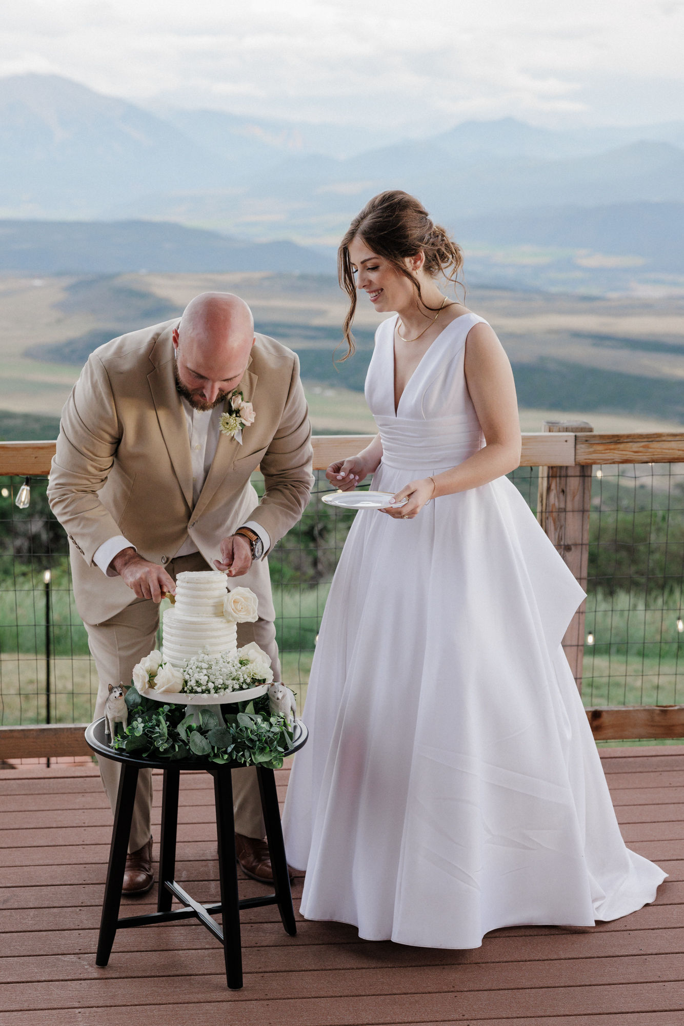 bride and groom cut wedding cake on the deck of a colorado airbnb